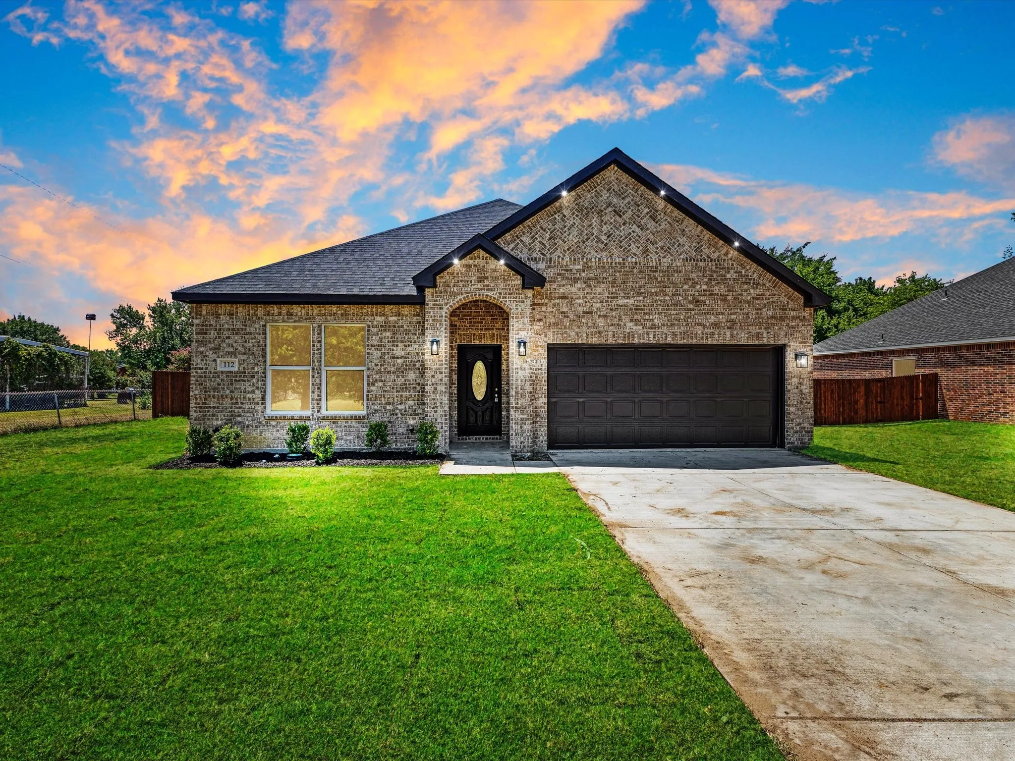 Brick exterior with an arched entry, two-car garage, and landscaped front yard