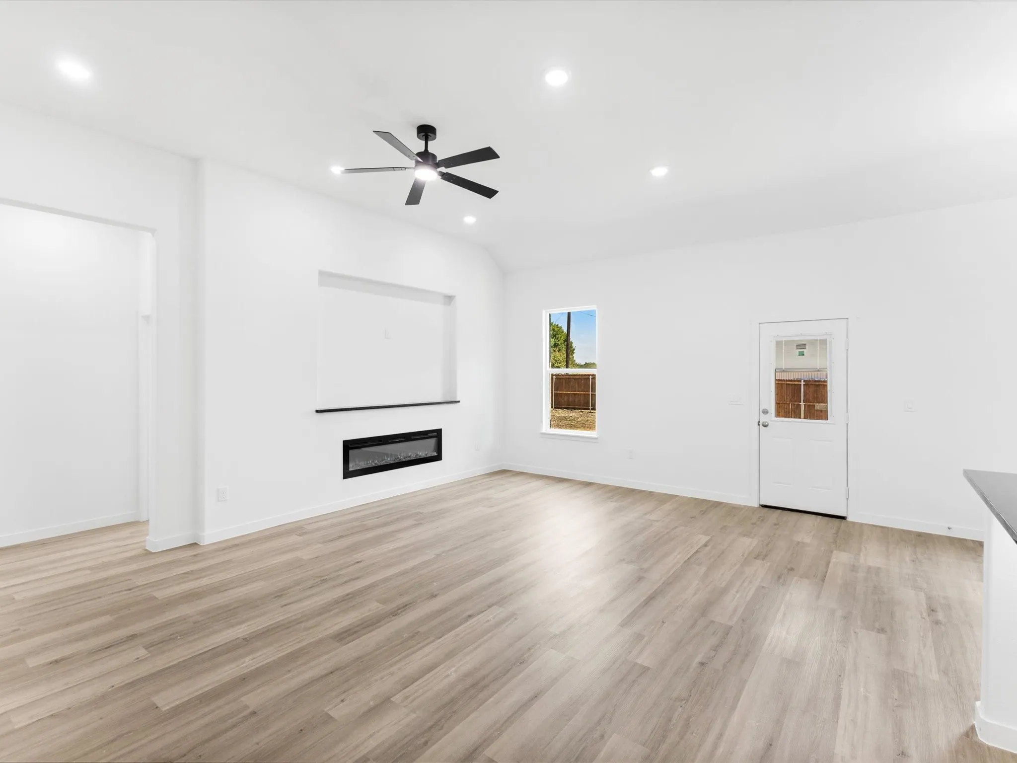 Integrated electric fireplace with a floating mantel, wood-finish flooring, recessed lighting, and a ceiling fan