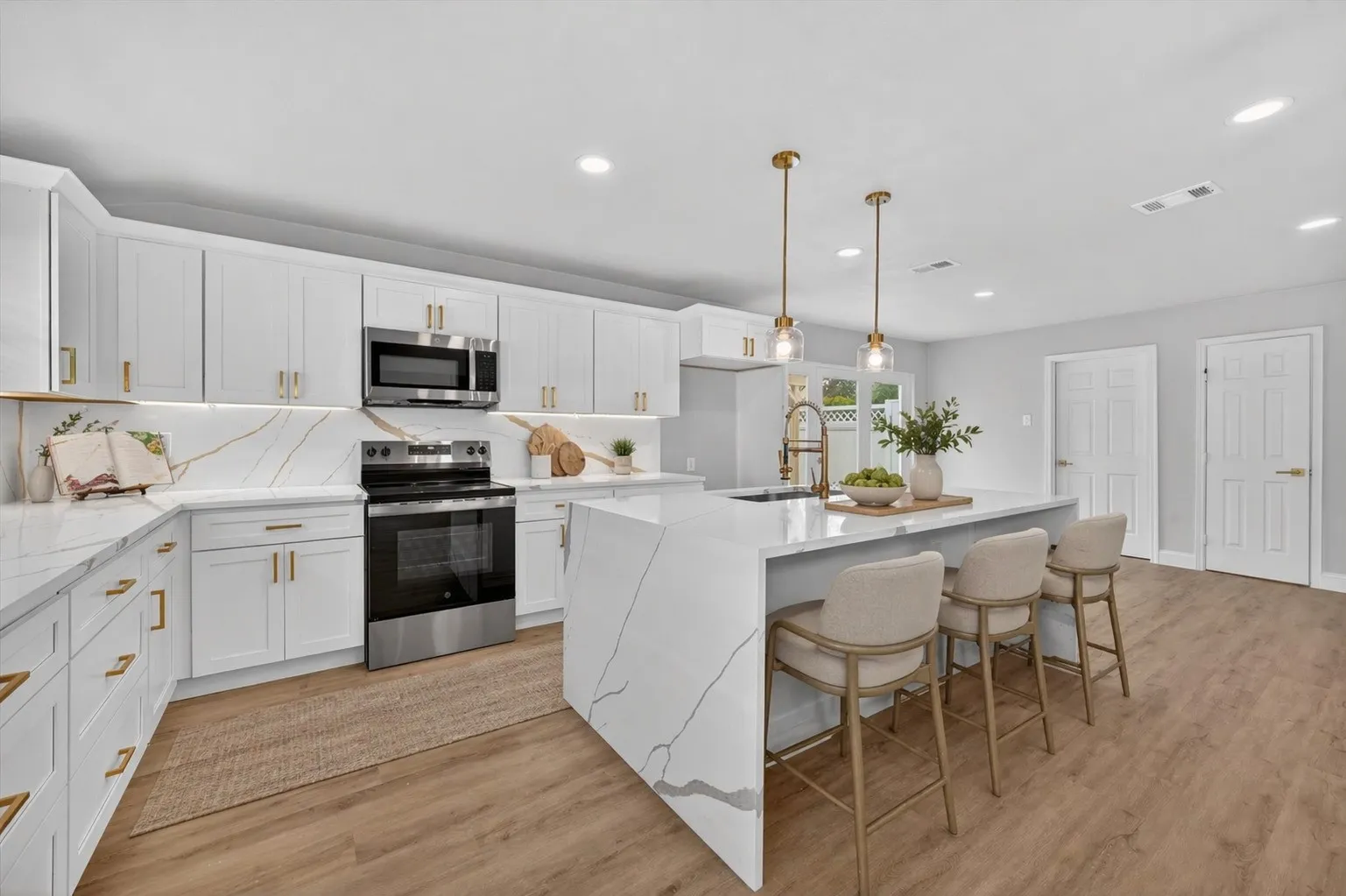 Modern kitchen featuring white cabinetry, gold-finish hardware, and wood-finish flooring