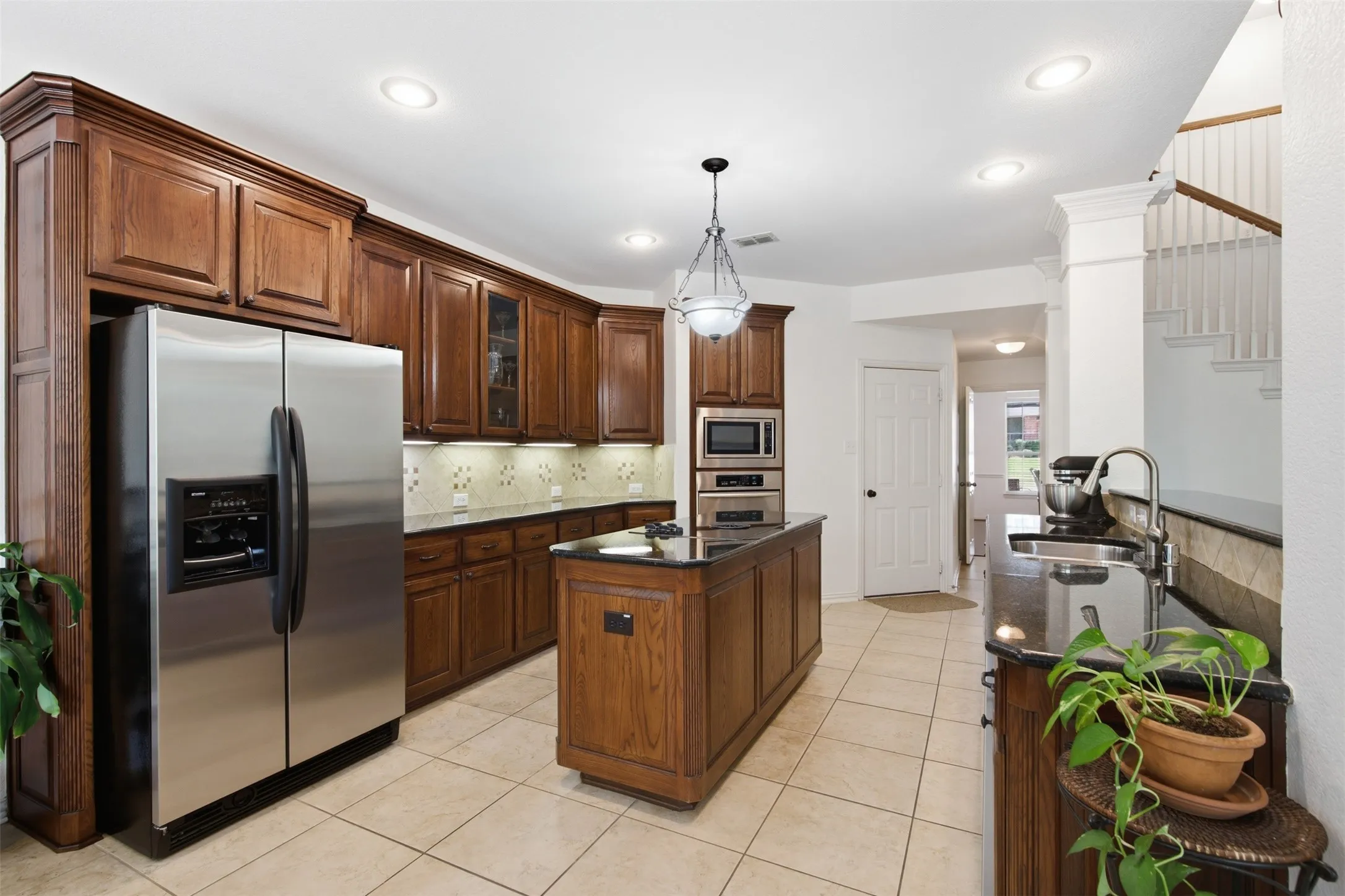 Kitchen featuring dark wood cabinetry, stainless steel appliances, and dark granite countertops