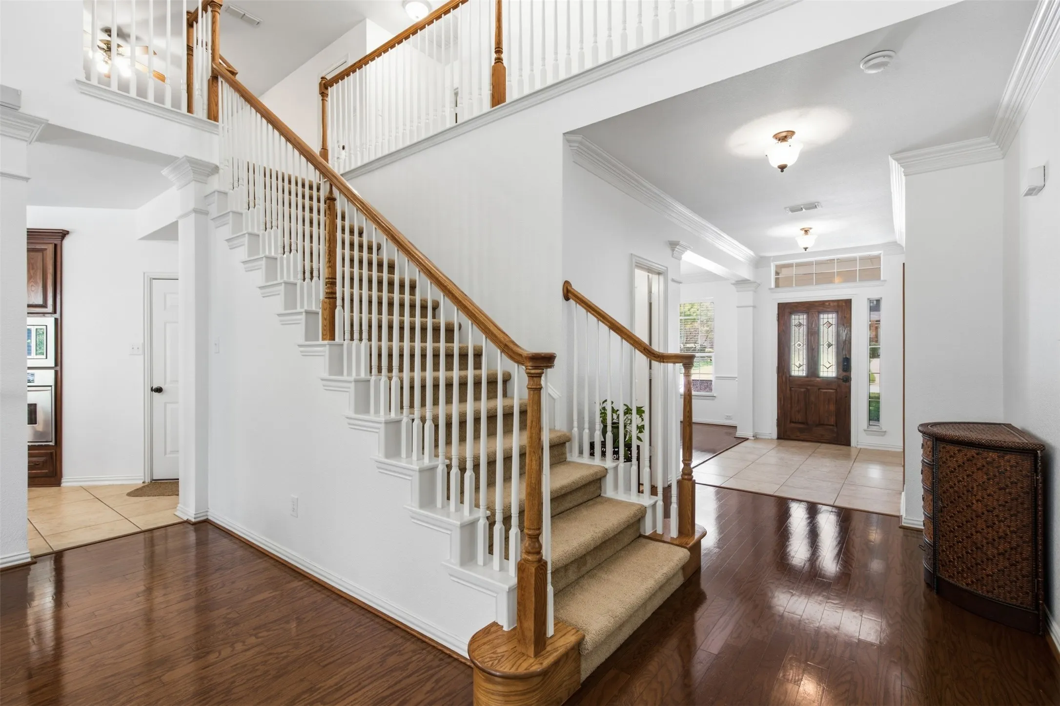 Spacious living area featuring high vaulted ceilings, rich wood-finish flooring, and a fireplace with a detailed mantel
