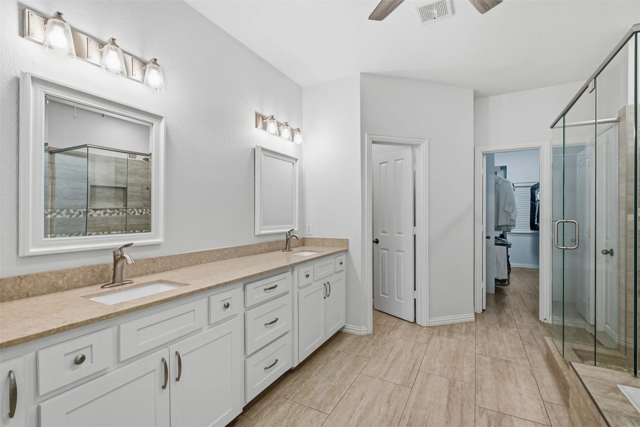 Spacious bathroom featuring a glass-enclosed shower with pebble-style flooring and a rain showerhead