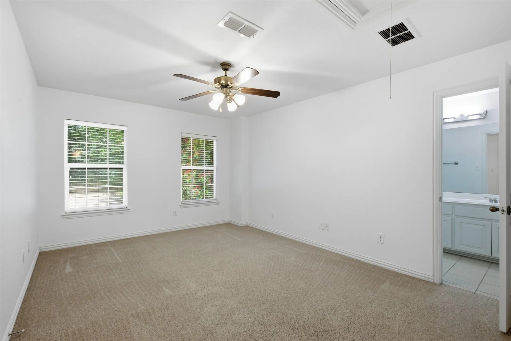 Carpeted bedroom with a single window, white walls, and a ceiling-mounted light fixture