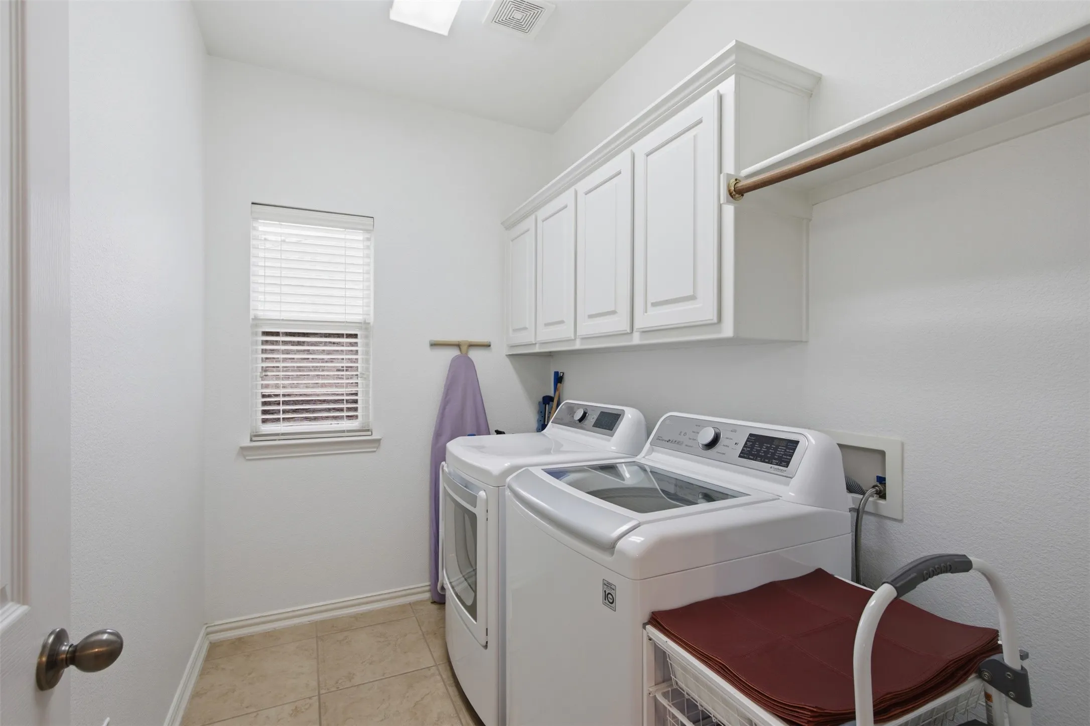 Bathroom featuring dual vanity with stone-finish countertops, white cabinetry, and brushed nickel fixtures