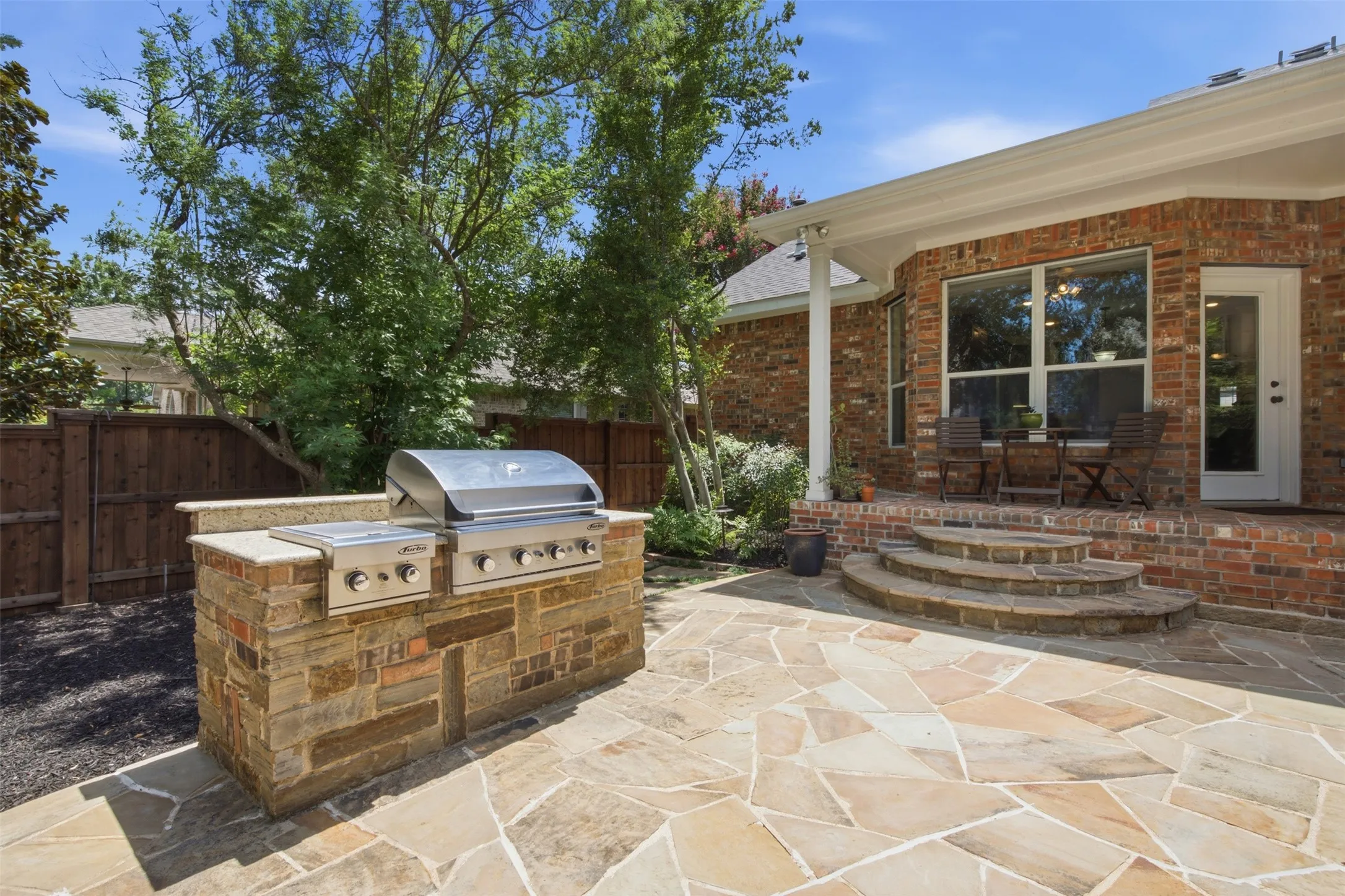 Curved swimming pool with integrated steps, surrounded by stone coping and concrete decking