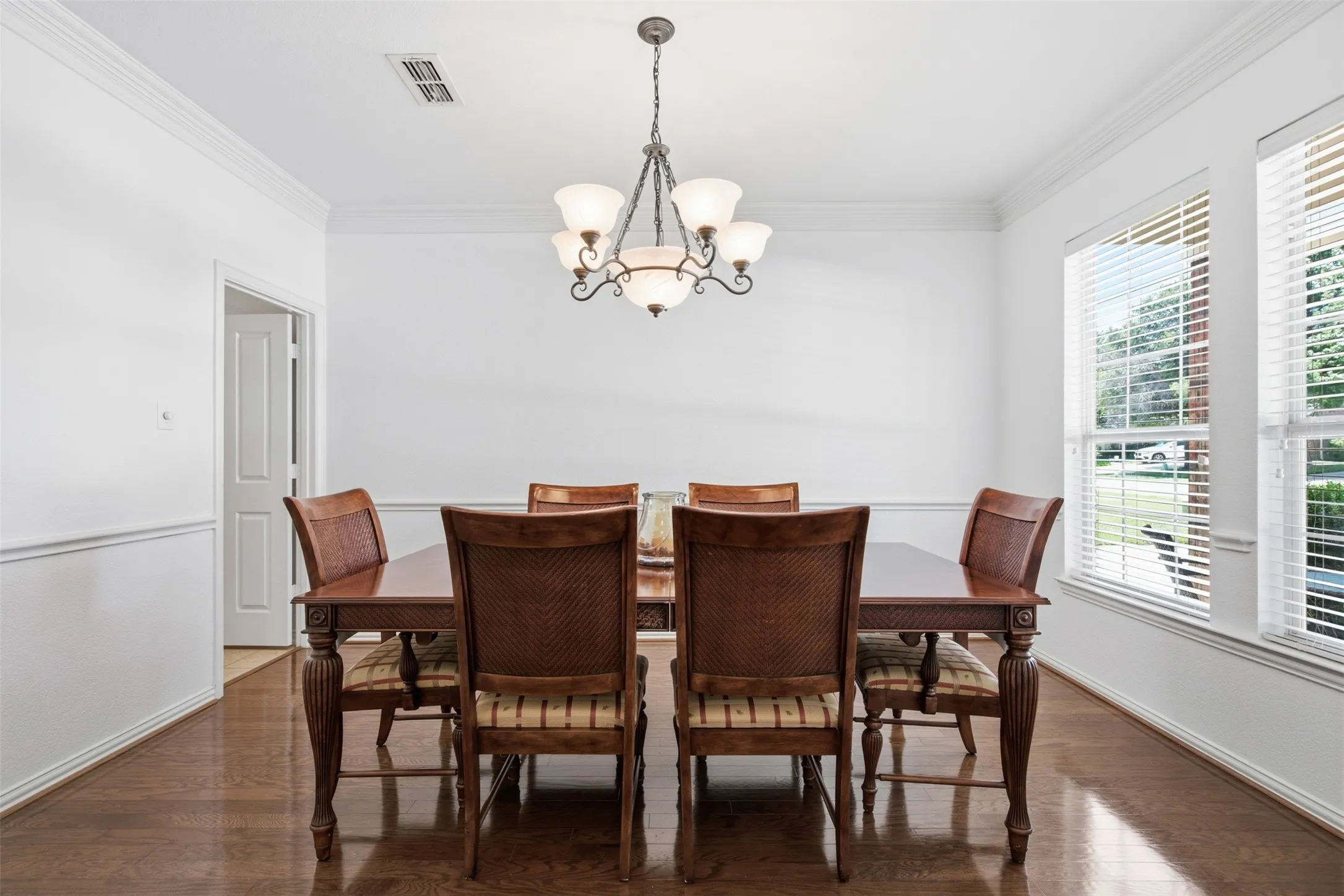 Spacious room featuring wood-finish flooring, white walls, and decorative crown molding
