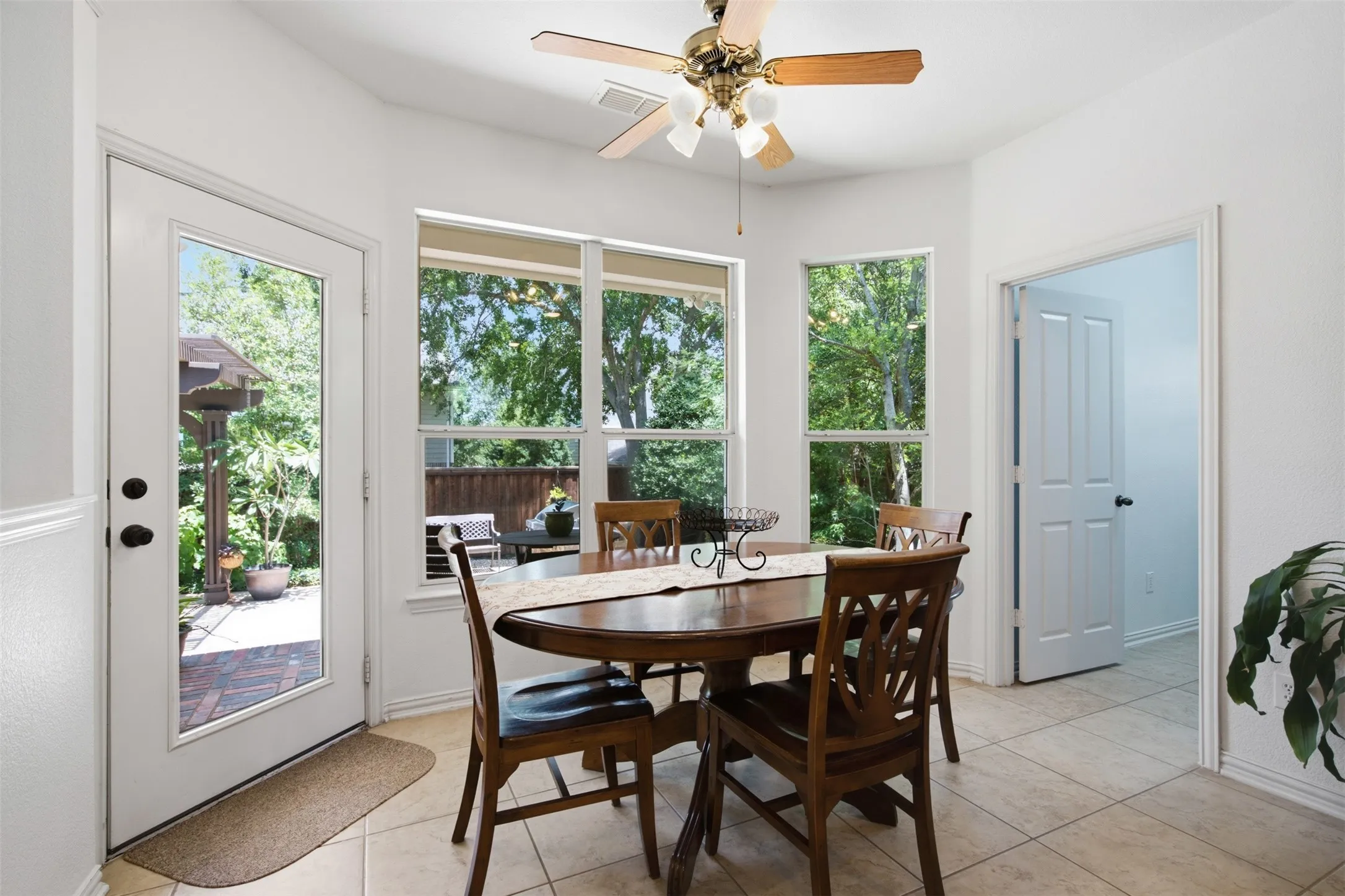 Spacious room featuring wood-finish flooring, three large windows with blinds, a ceiling fan, and crown molding