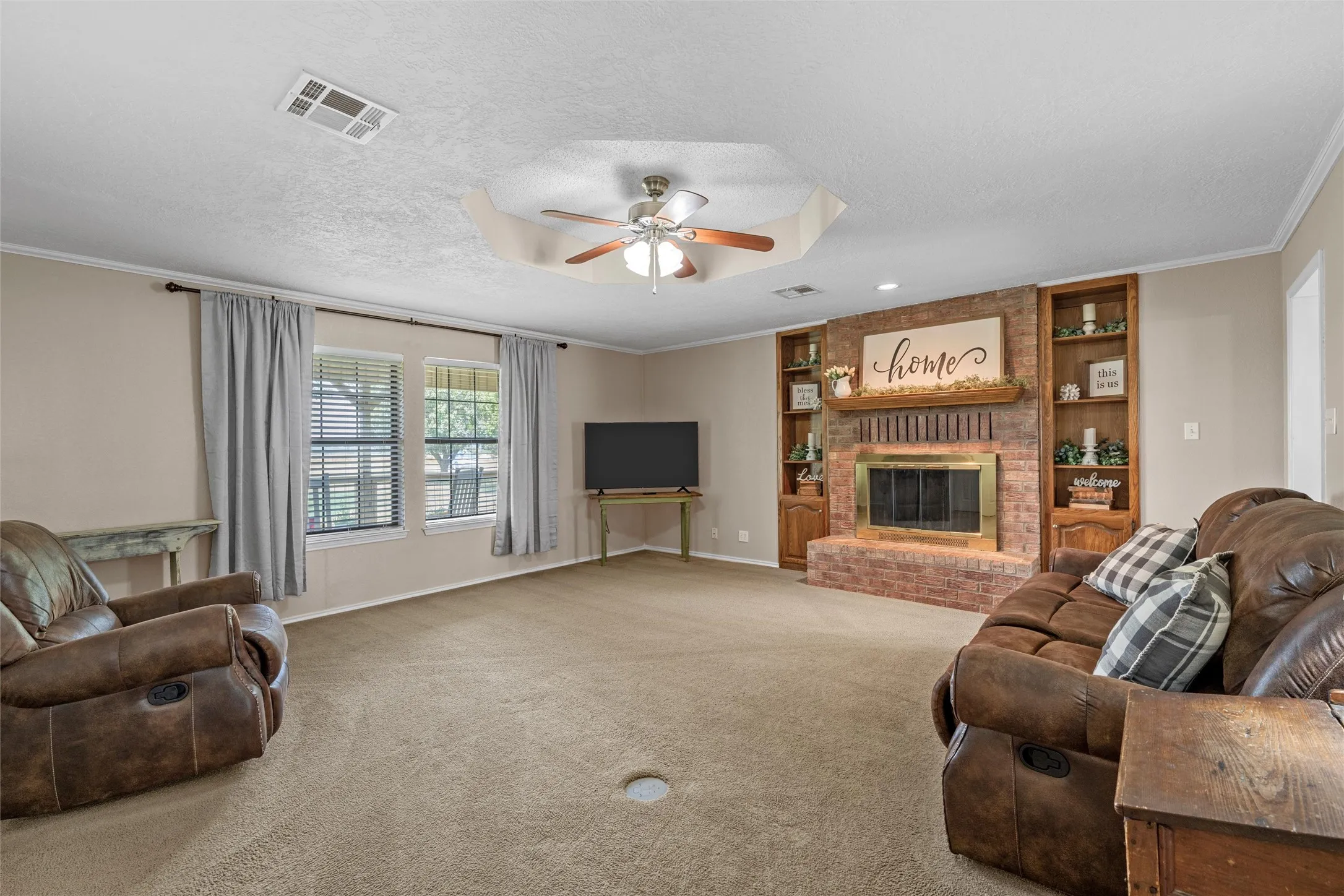 Brick fireplace with a brass firebox and wood mantle, flanked by built-in wood shelving