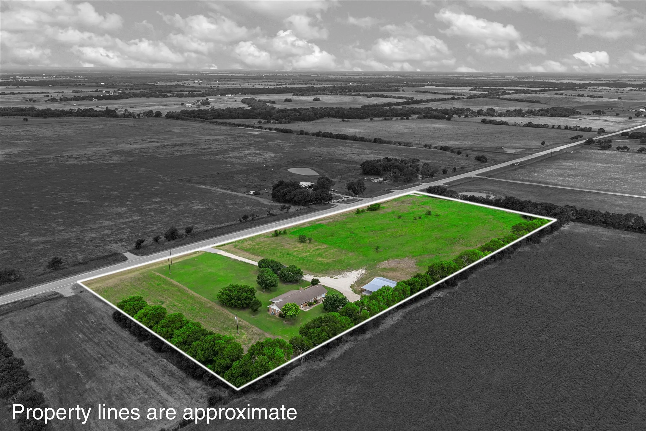 Expansive rural property featuring a single-story residence, a detached auxiliary structure, and substantial green space