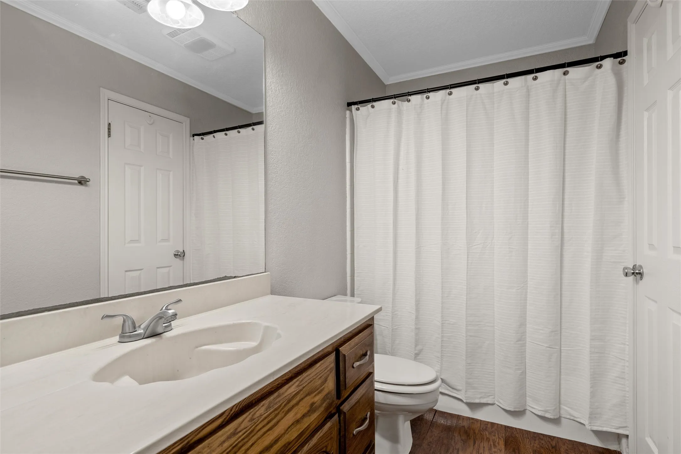 Bathroom featuring a vanity with a white countertop and wood-finish cabinetry, chrome faucet, and integrated sink