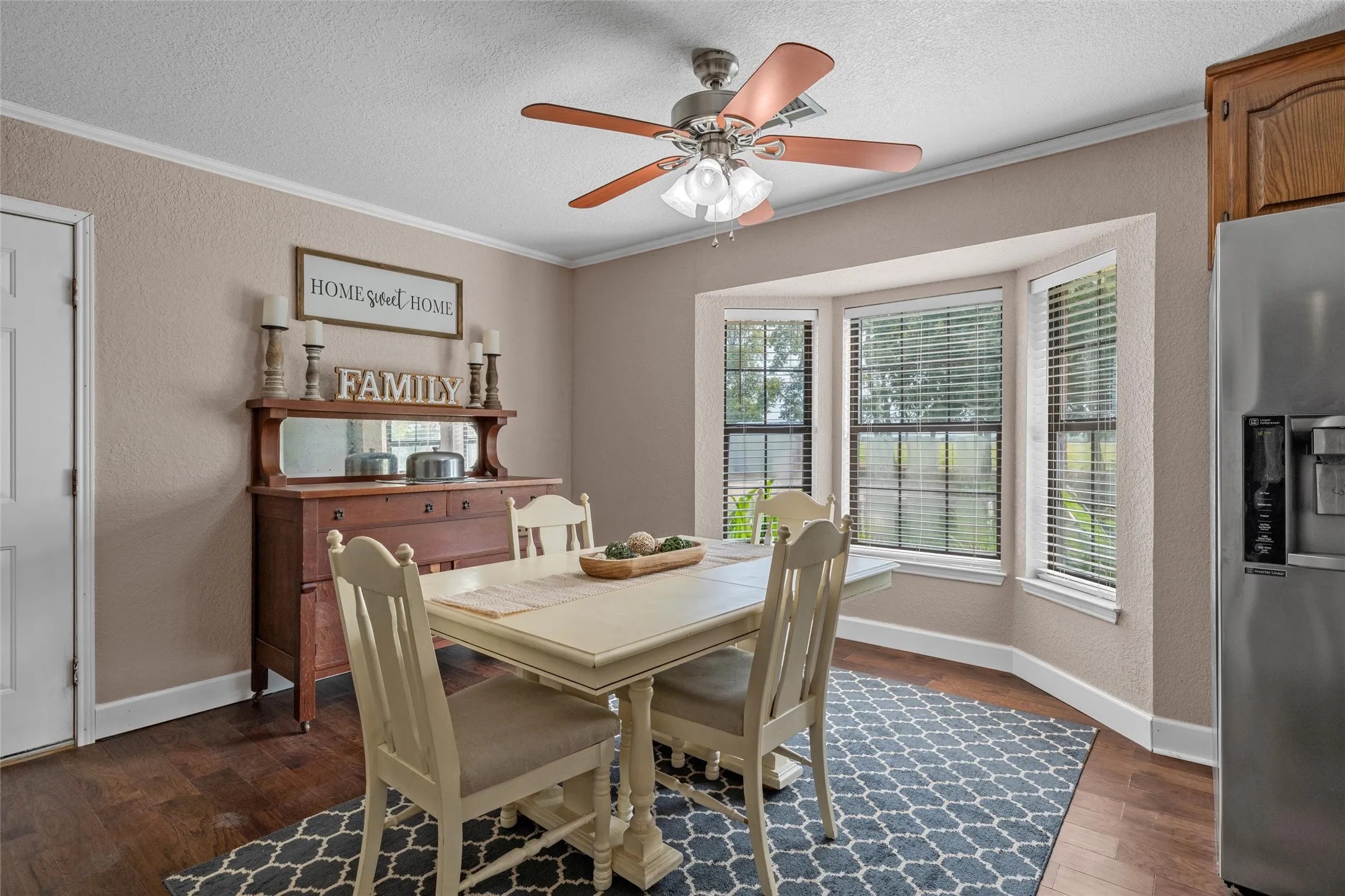 Dining area featuring a bay window, wood-finish flooring, and a ceiling fan