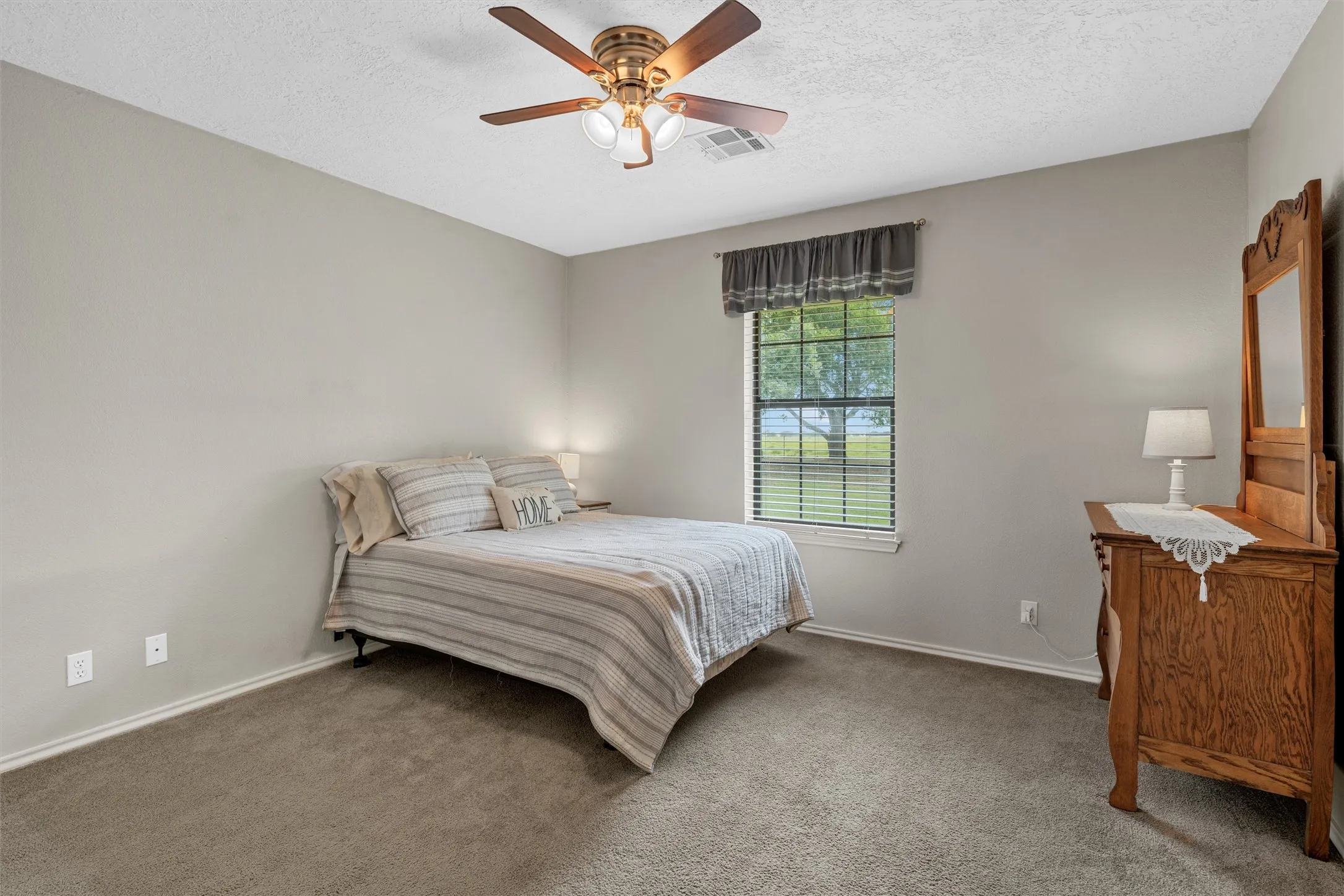 Carpeted room featuring a ceiling fan with integrated lighting, a window with horizontal blinds, and neutral-toned walls