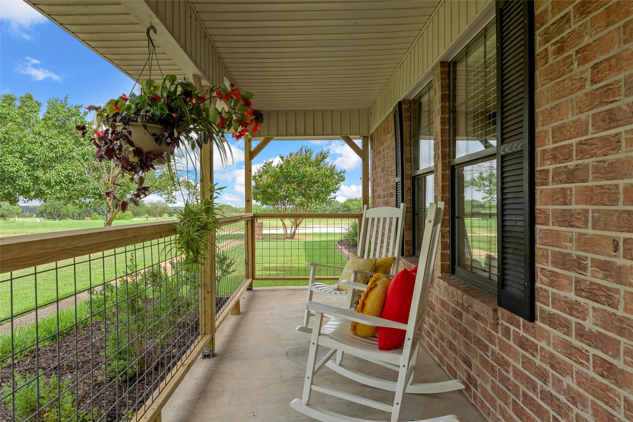 Covered front porch featuring a brick exterior and black louvered shutters