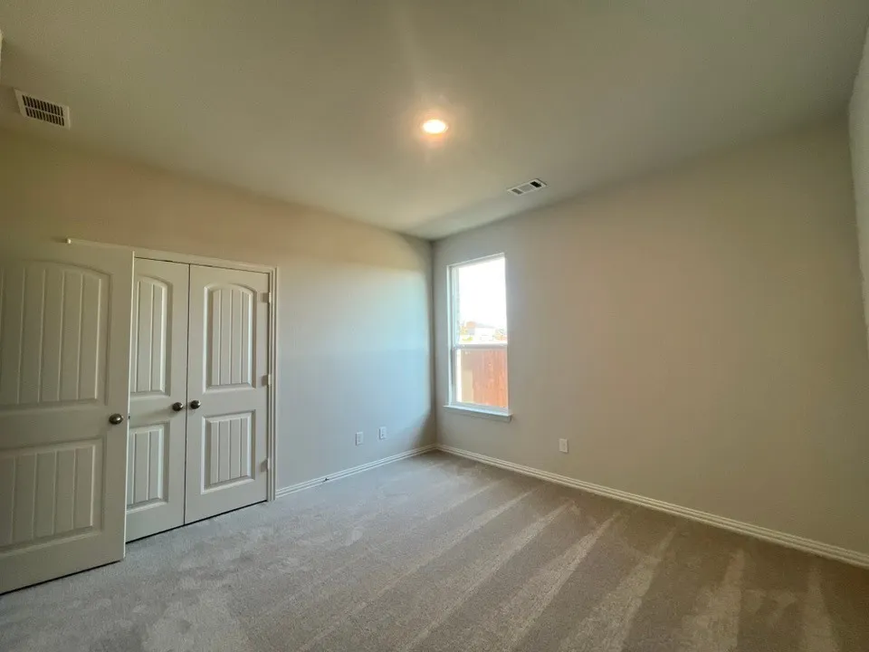 Light neutral wall paint, recessed ceiling lighting, light-colored carpeting, white trim, and a window with white casing