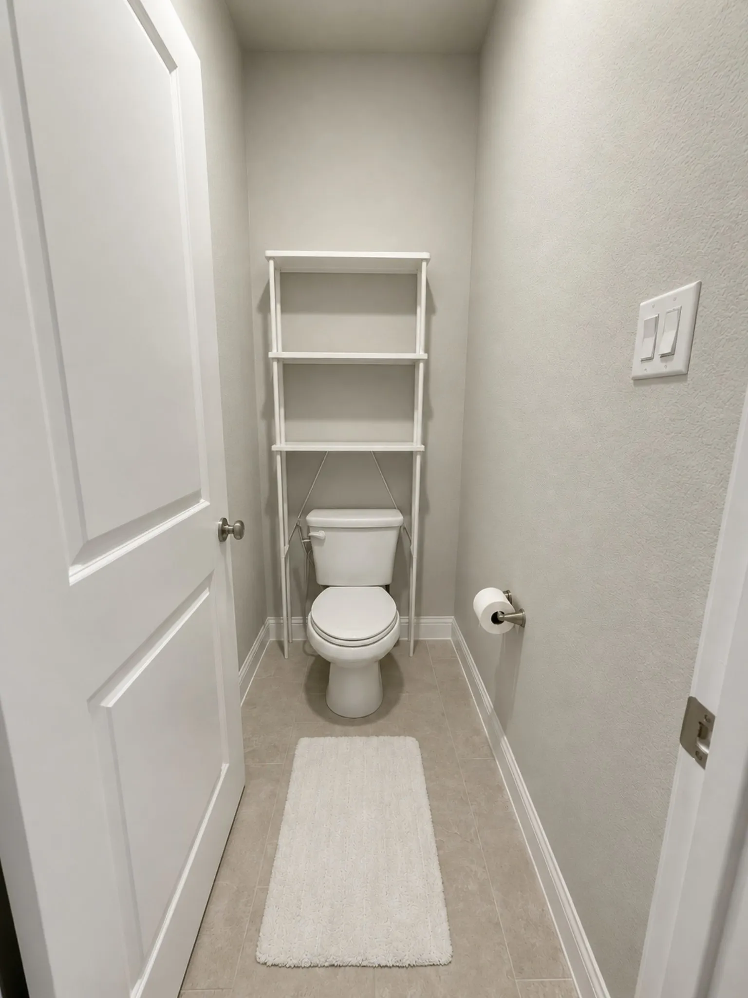 Powder room featuring a white toilet, tile flooring, and light gray walls