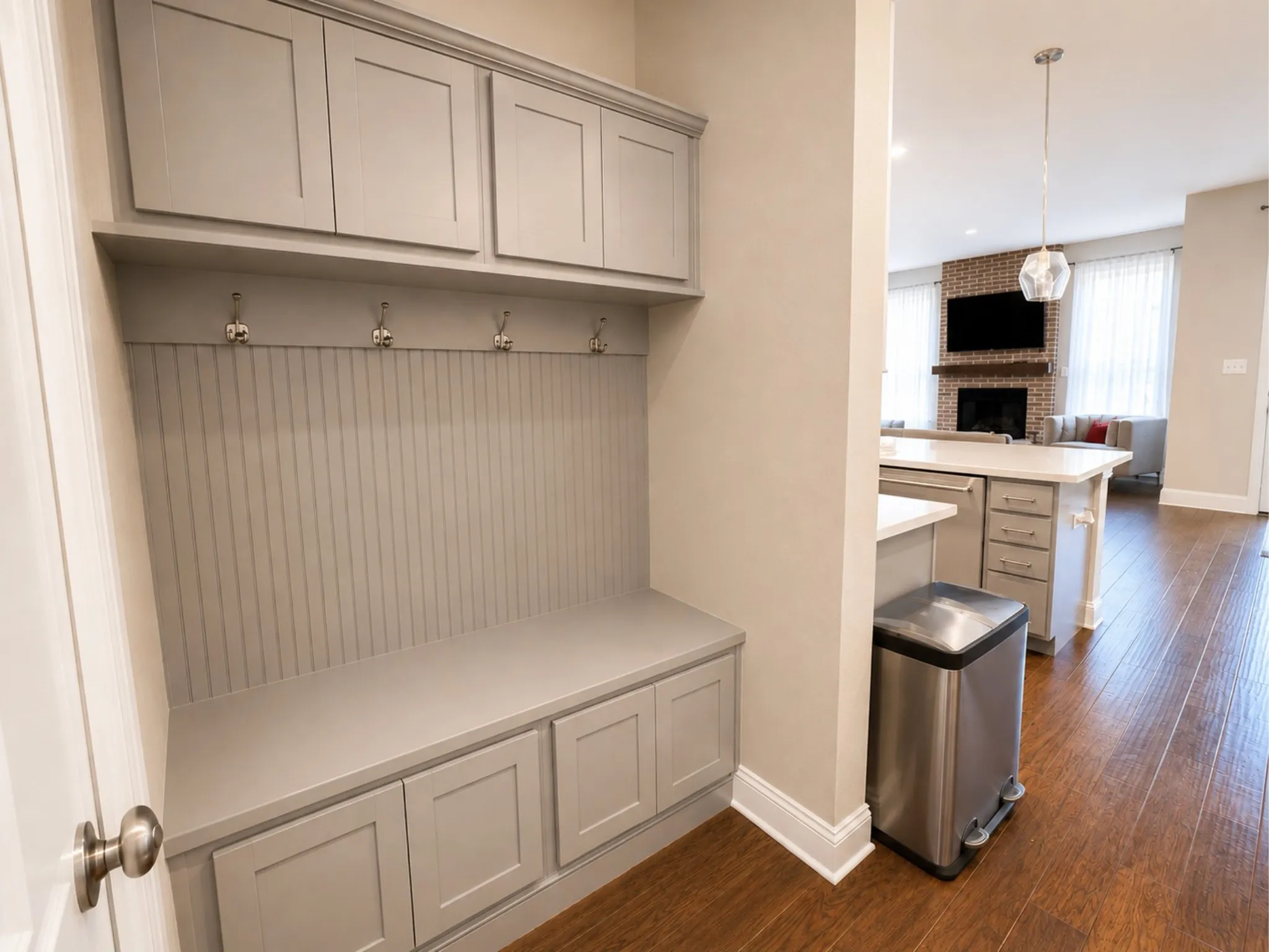 Built-in entryway storage with upper cabinetry, beadboard backing, and bench seating with integrated lower storage