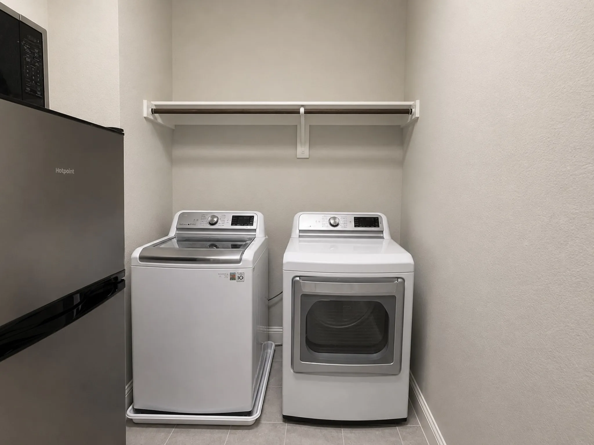 Dedicated laundry area featuring a white top-load washer, a white front-load dryer, and a wall-mounted shelving unit