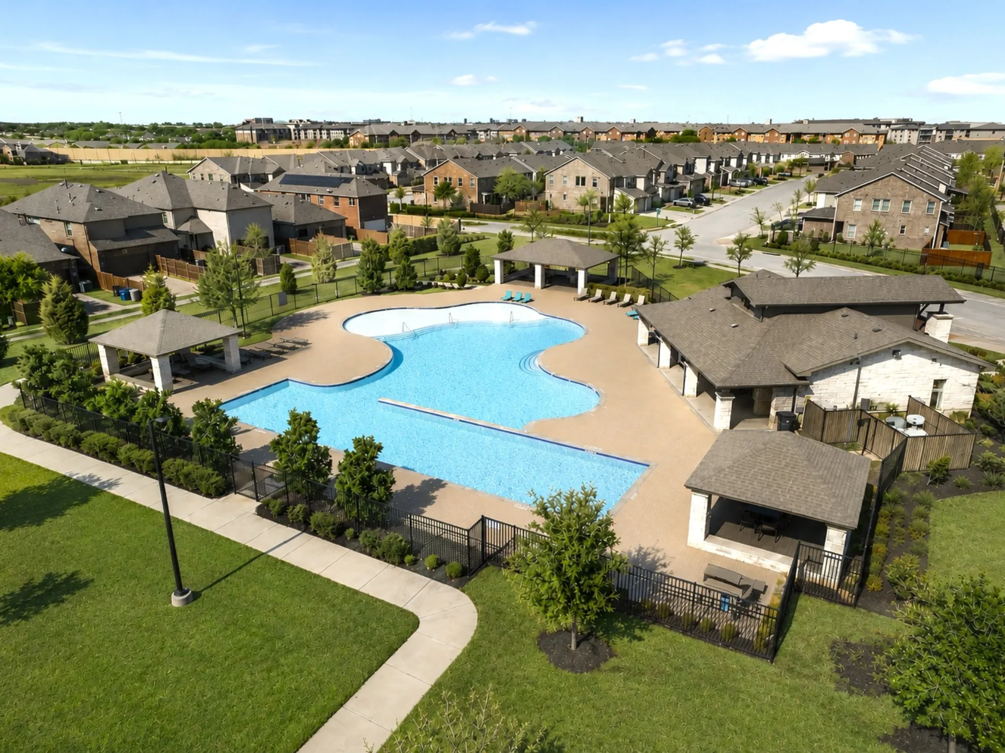 Resort-style pool area featuring multiple shaded cabanas, extensive paved decking, and a stone-clad clubhouse structure