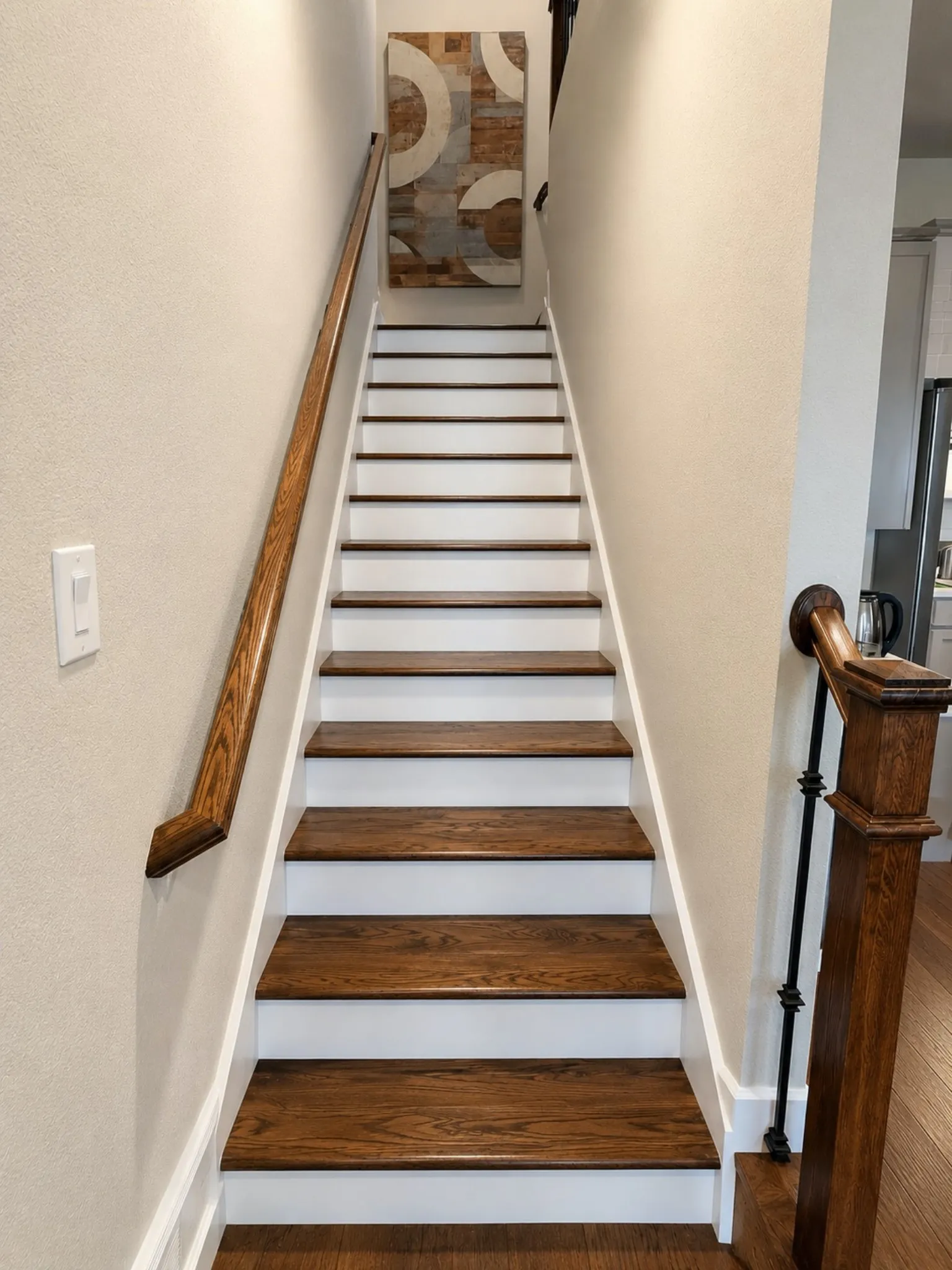 Staircase featuring wood-finish treads, white risers, and a coordinating wood-finish handrail