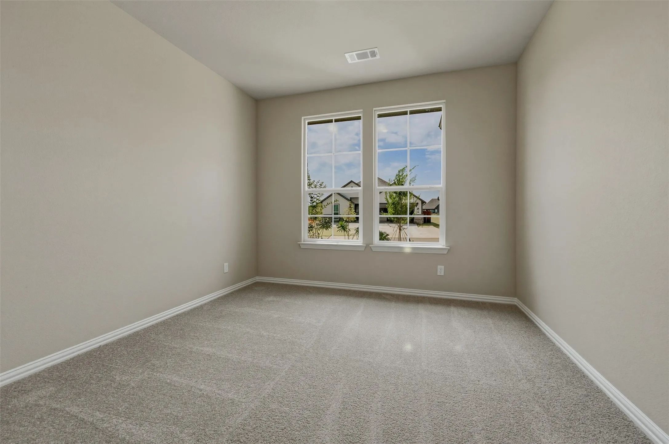 Gray carpeted flooring, light neutral-toned walls, and two large windows