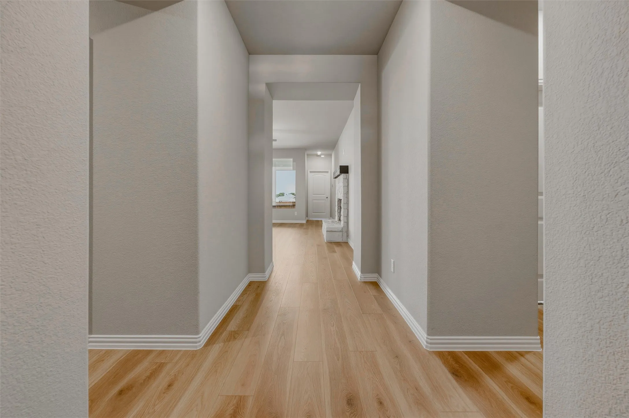 Archways defining a neutral-toned hallway with wood-finish flooring and white trim