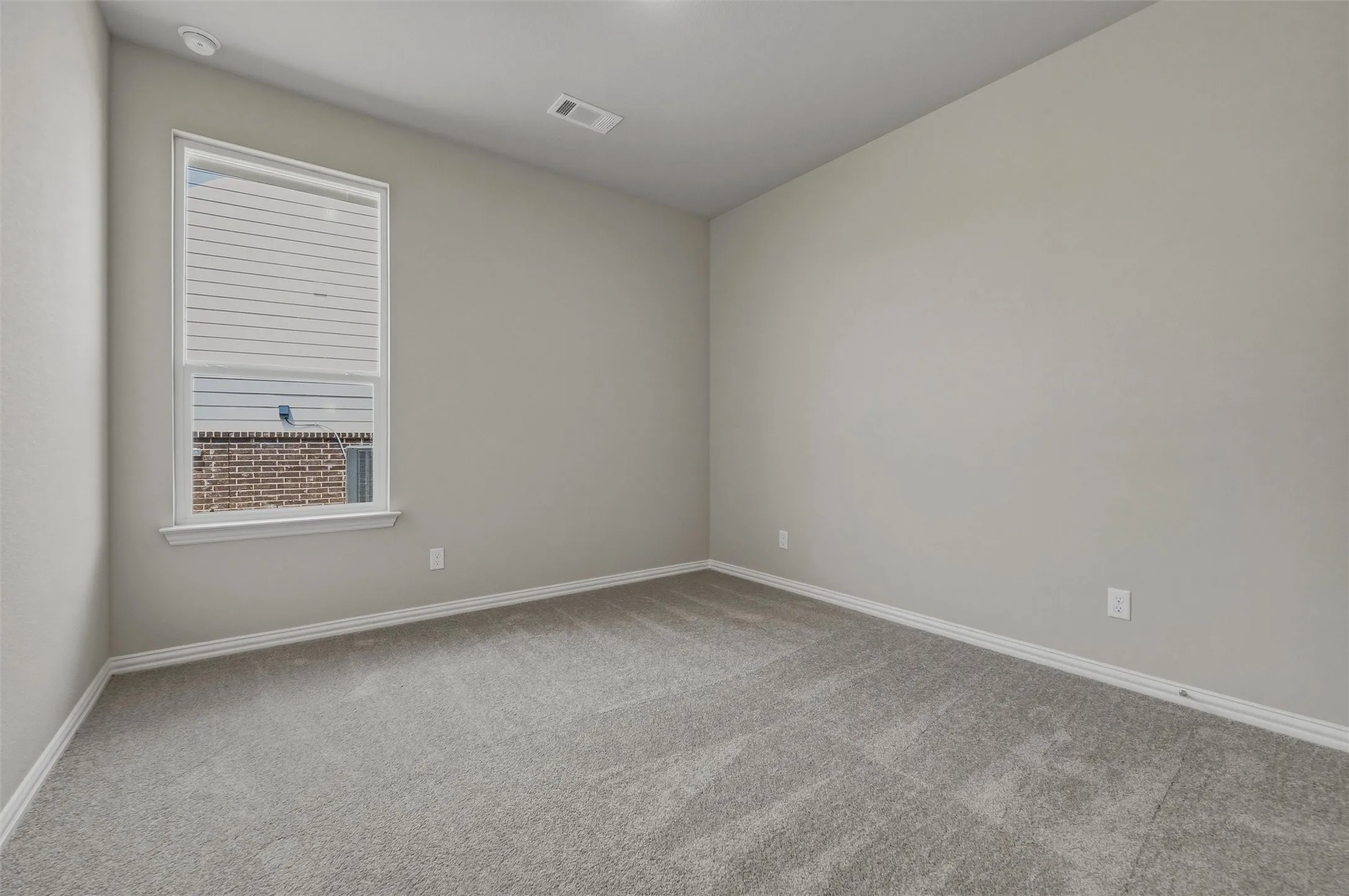Neutral tone paint throughout, plush carpet flooring, white trim, and a window with blinds