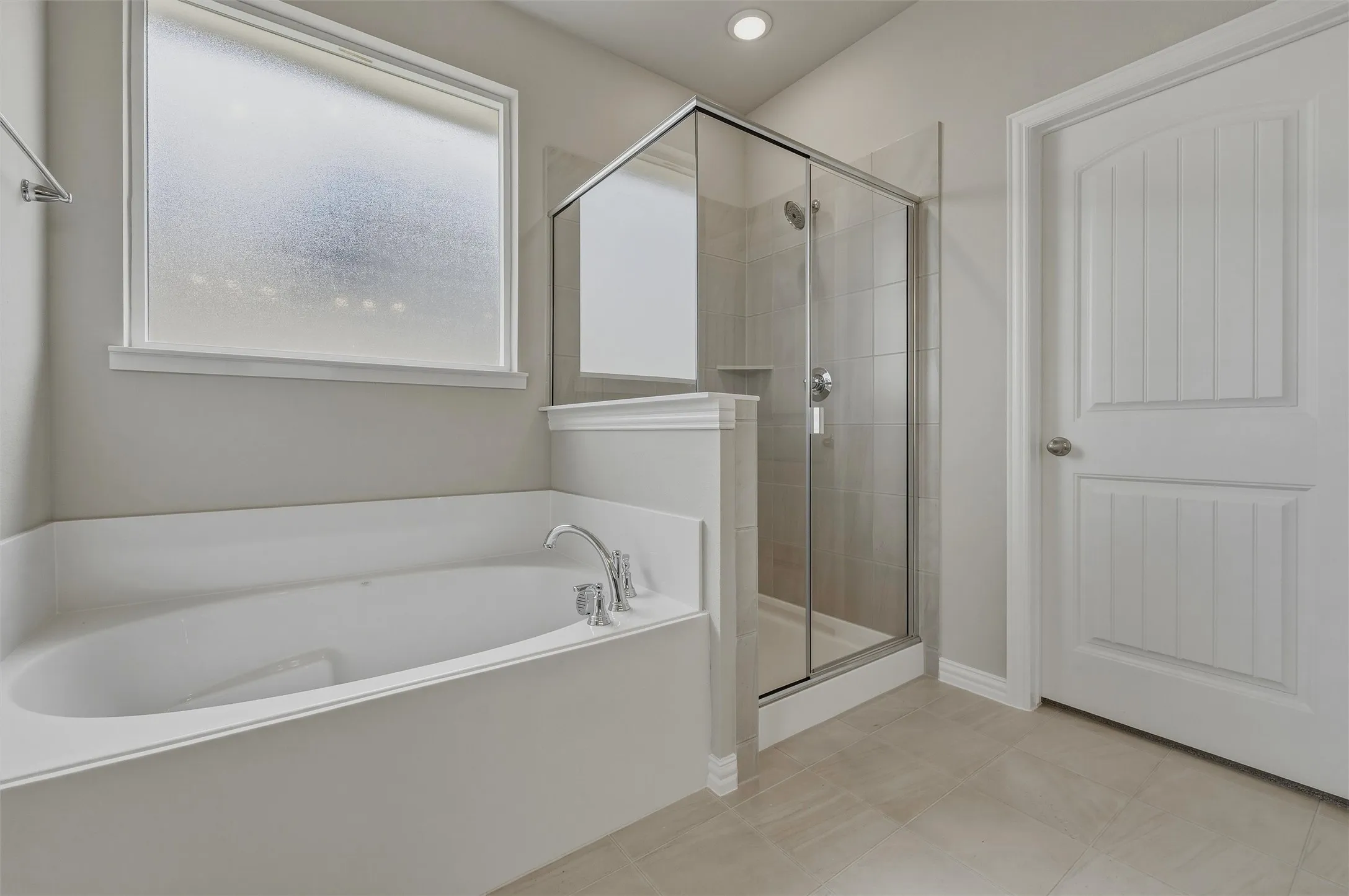 Soaking tub with polished chrome fixtures, separate glass-enclosed shower, tiled shower surround, recessed lighting, and tile flooring