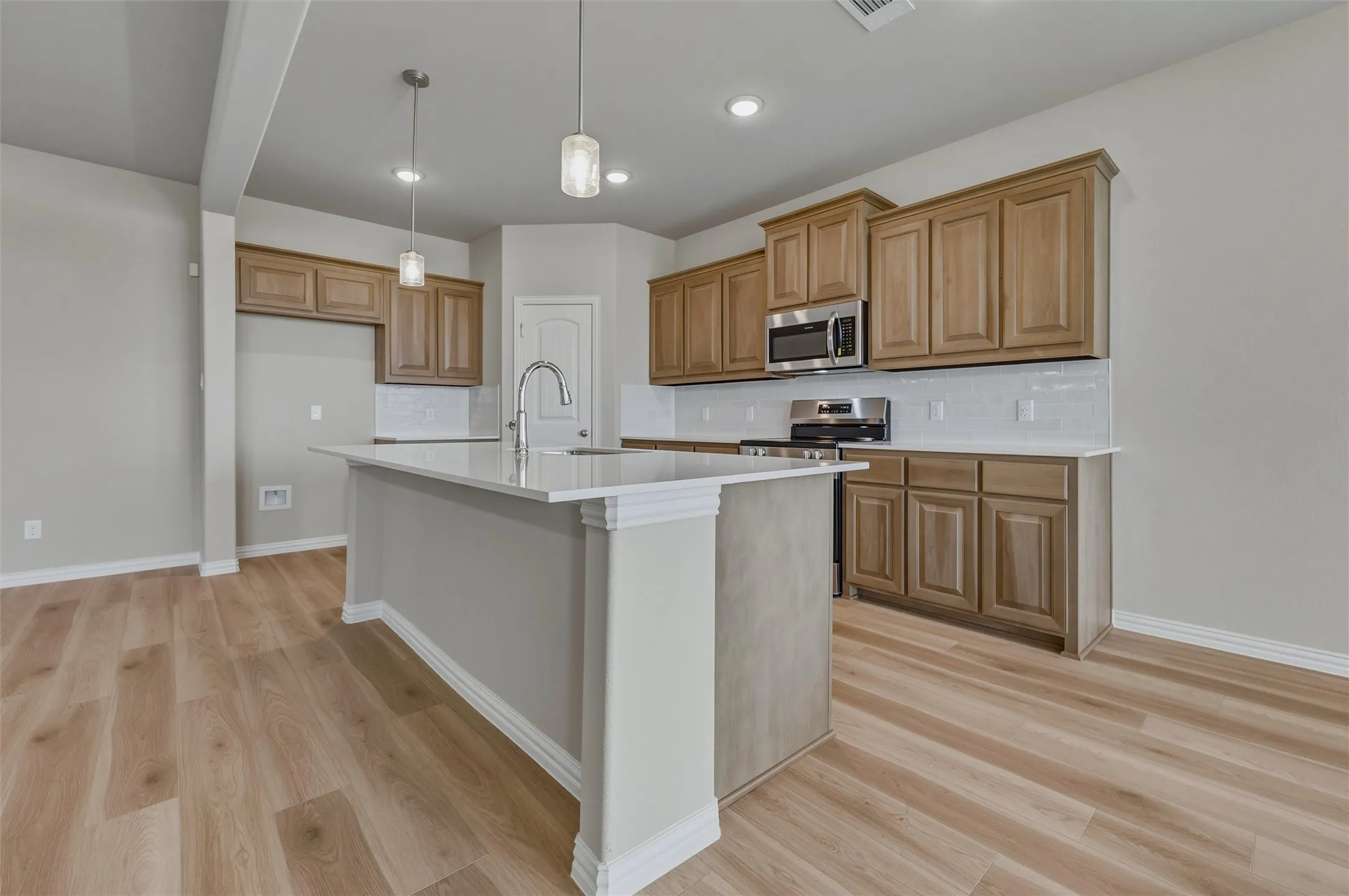 Kitchen featuring wood-finish flooring, a central island with countertop, recessed lighting, pendant lighting, and stainless-steel appliances