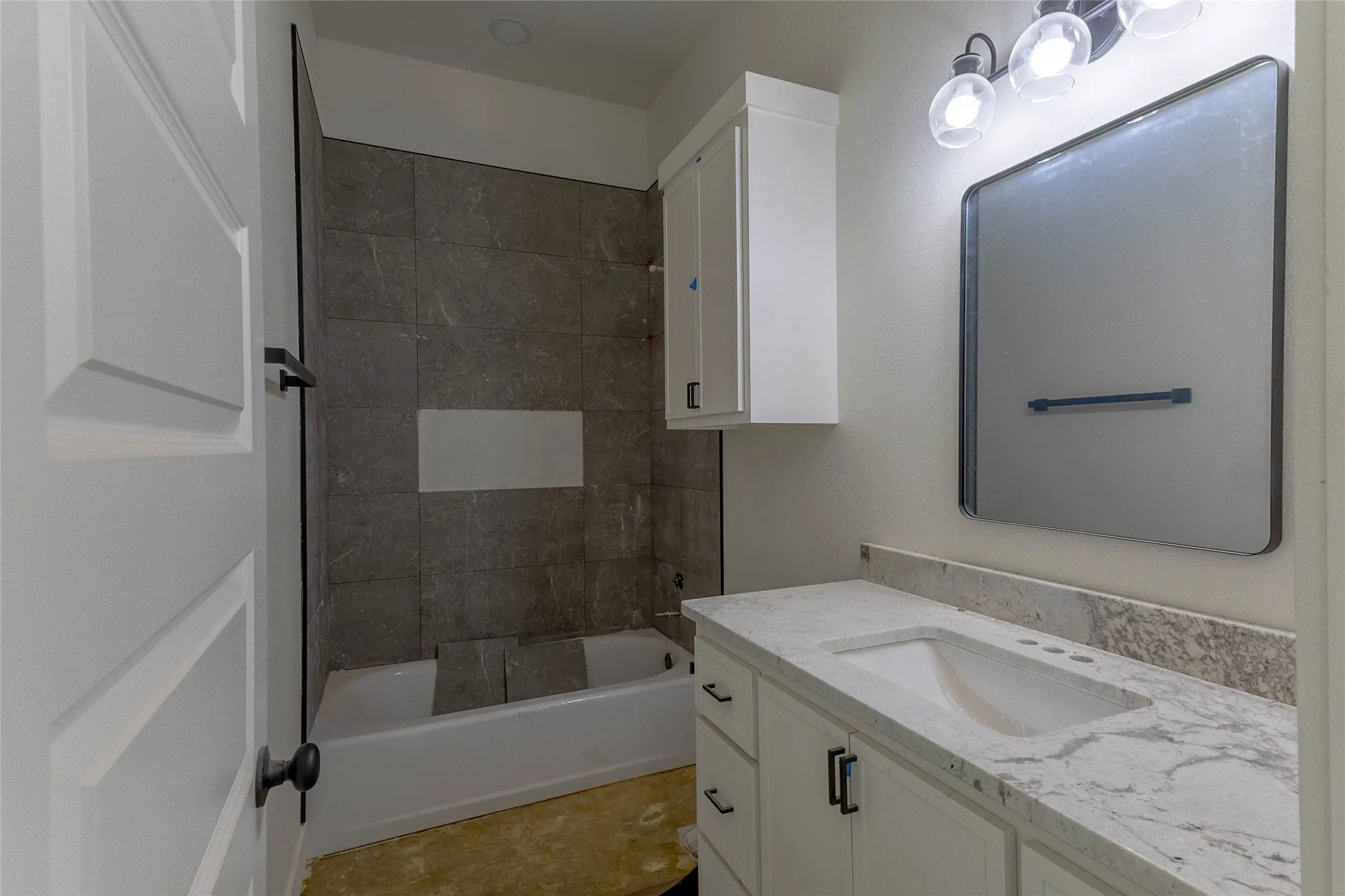White vanity with a single basin sink, light-toned countertop, and integrated backsplash