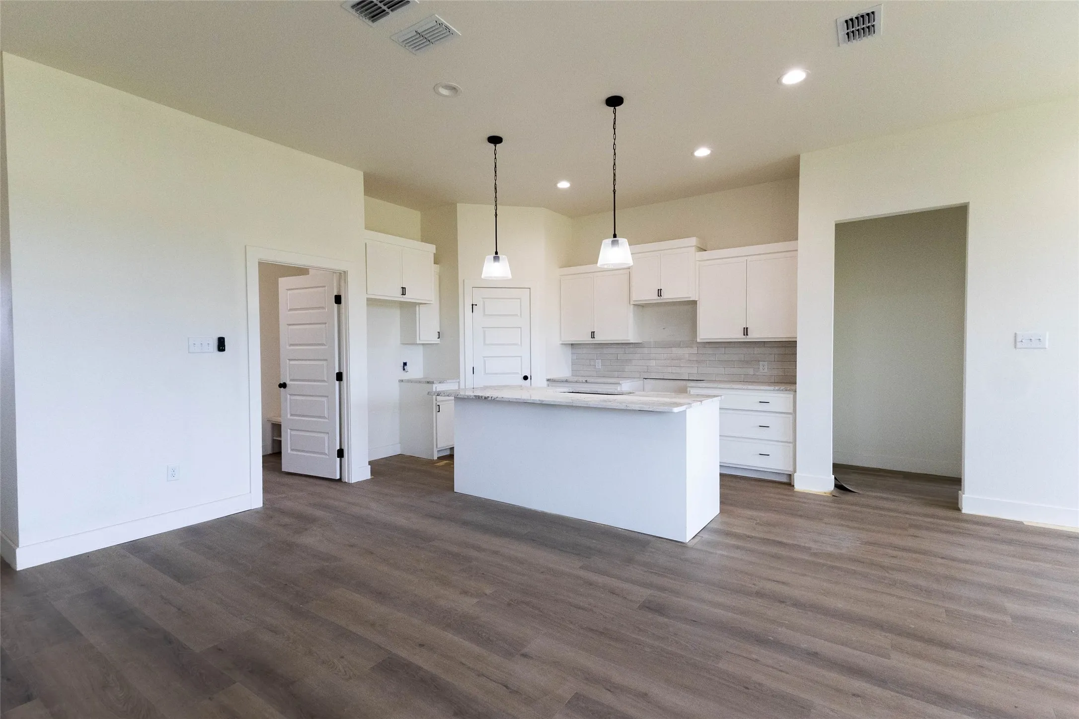 Open-concept kitchen with a central island, white cabinetry, undermount sink, and pendant lighting