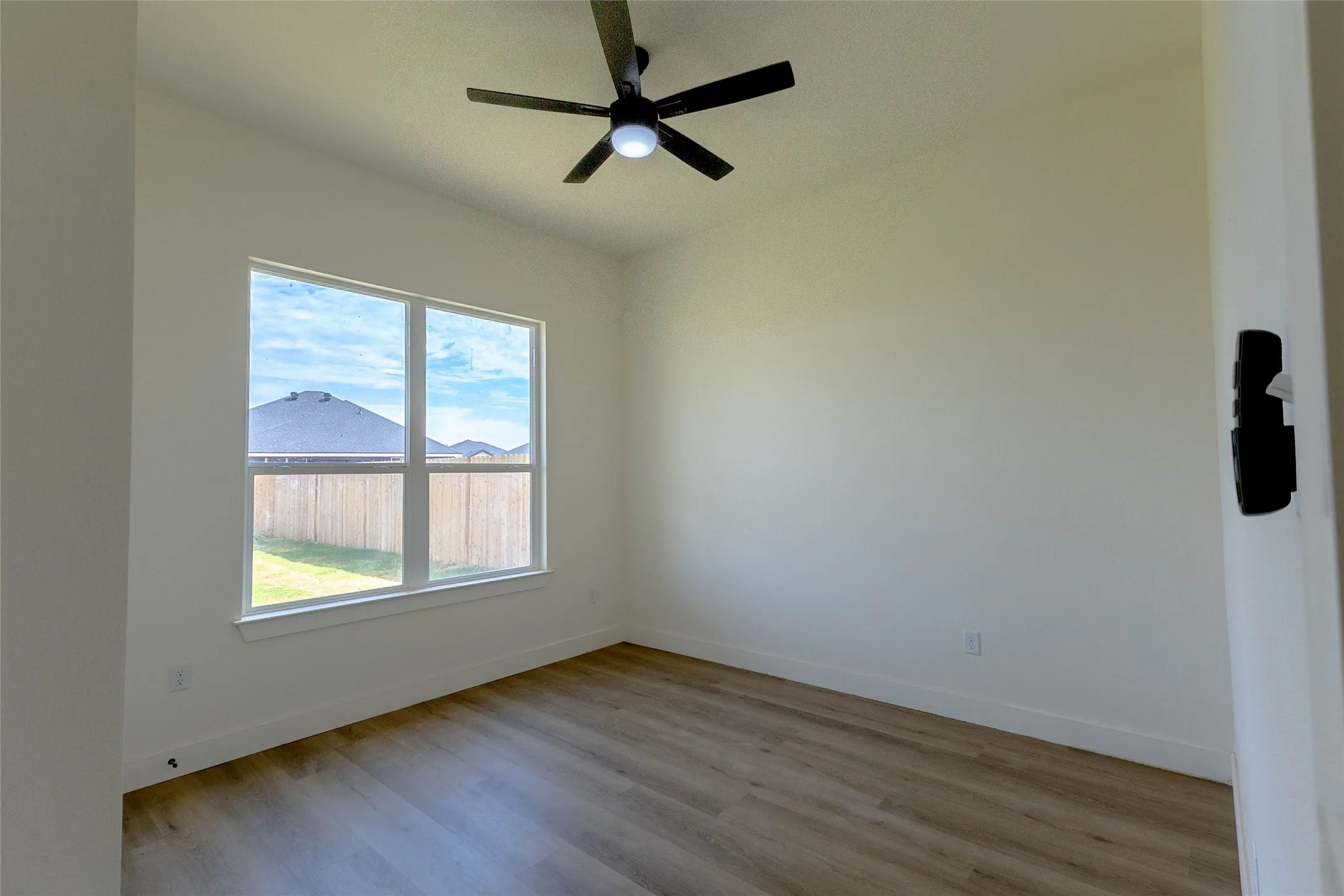 Neutral wall paint, wood-finish flooring, and a contemporary ceiling fan