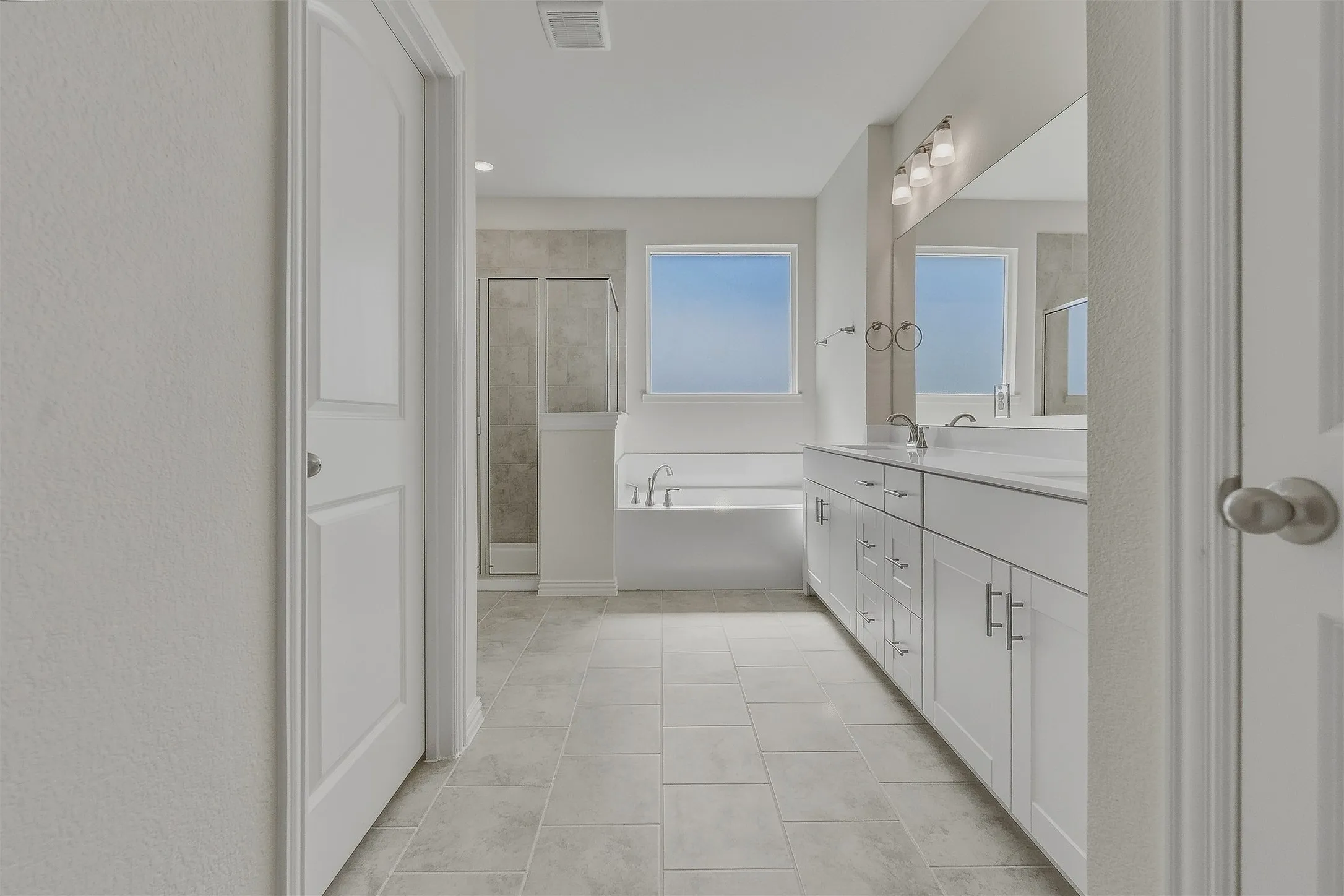 Dual vanity with white cabinetry, integrated sinks, and a wide mirror