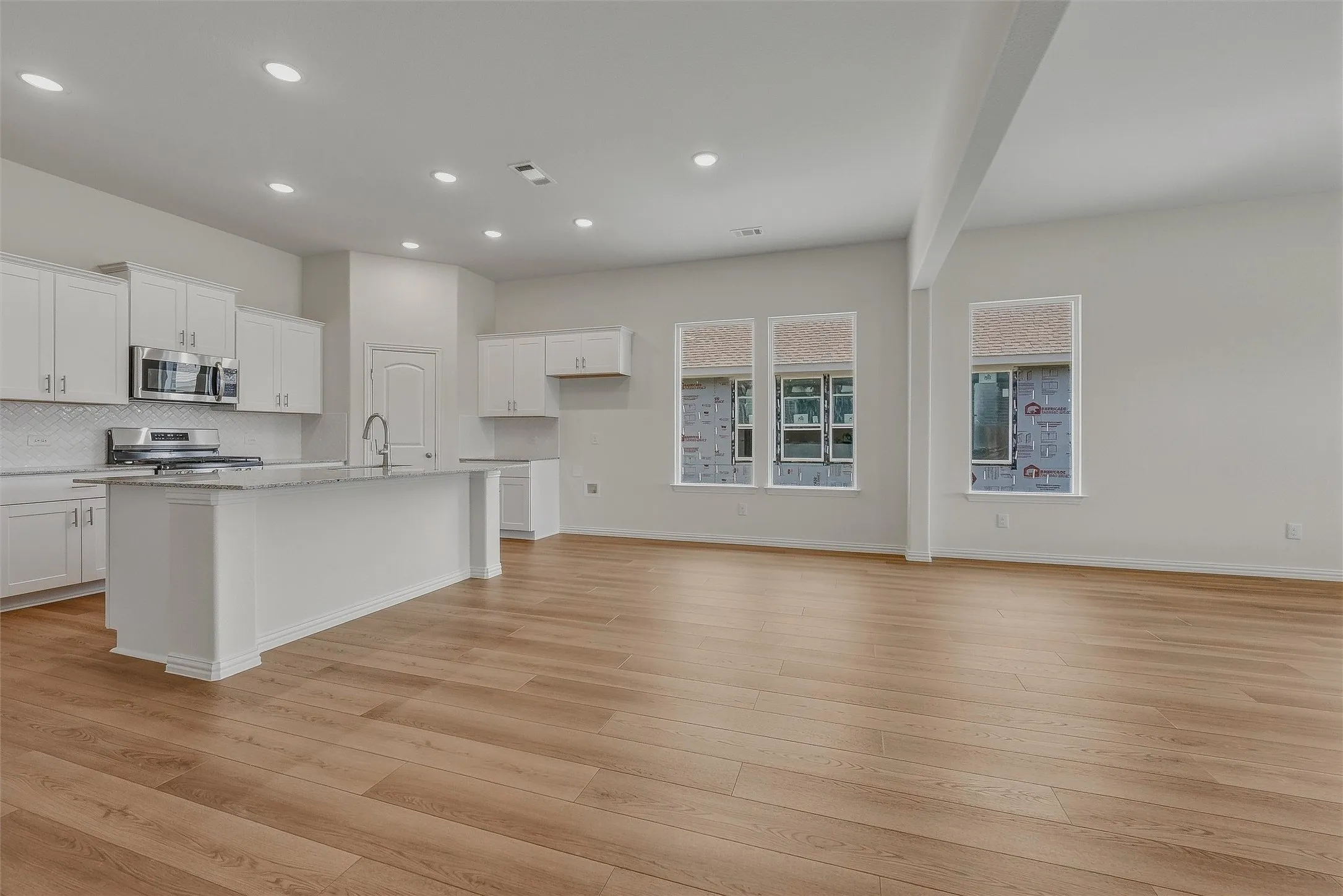 Open-concept living space featuring wood-finish flooring, recessed lighting, and multiple windows