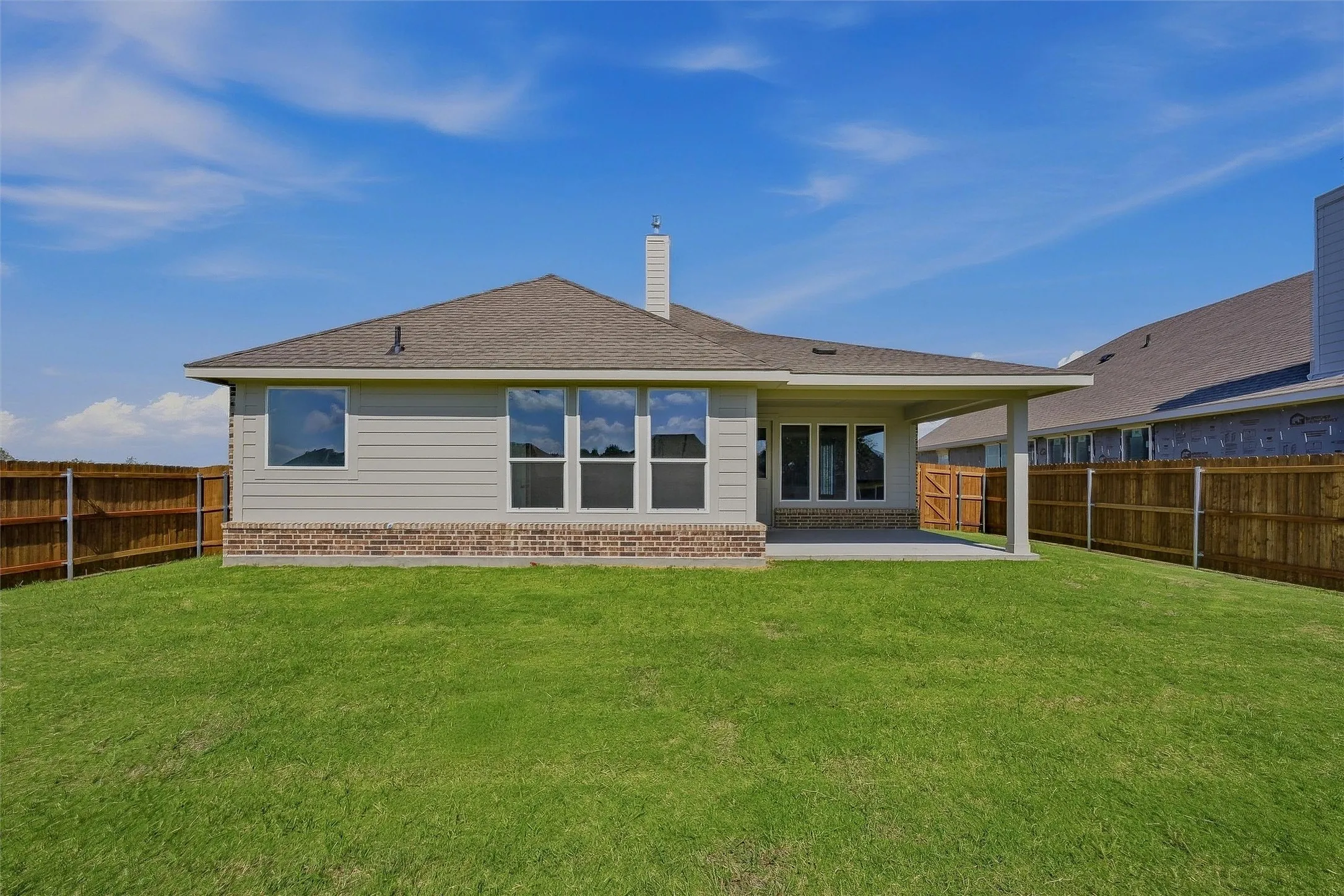 Expansive backyard featuring a covered patio, a brick and siding exterior, and a privacy fence