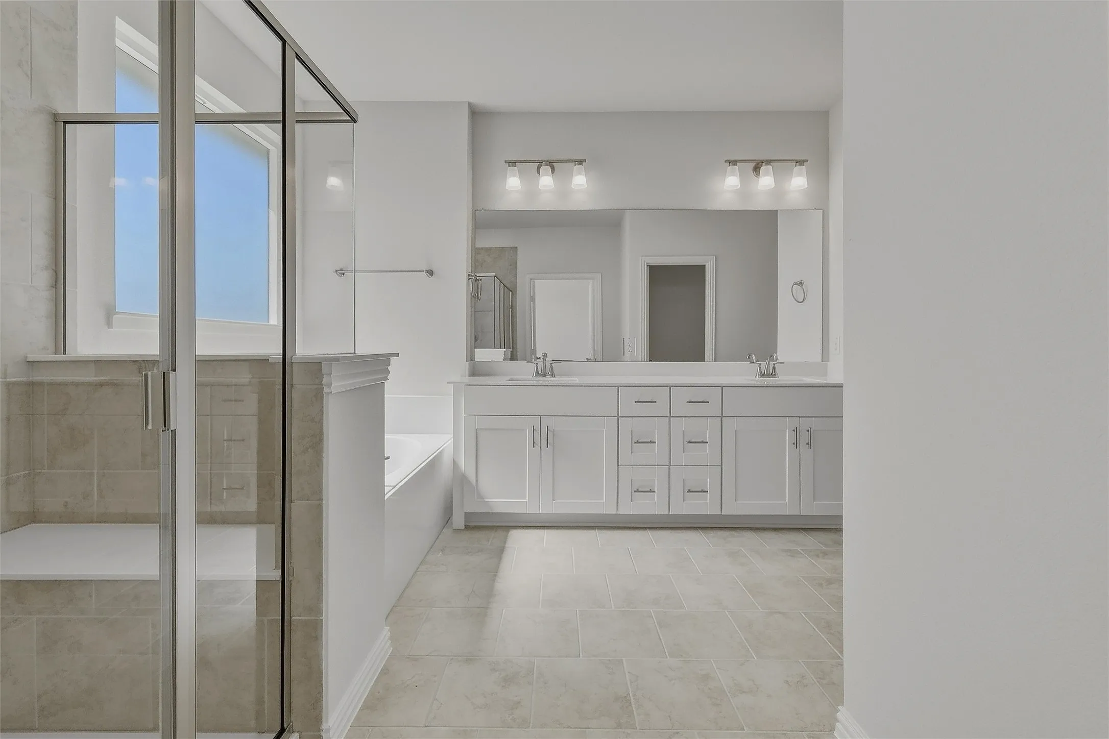 Frameless glass shower enclosure with built-in bench, soaking tub, dual vanity with undermount sinks, and tile flooring