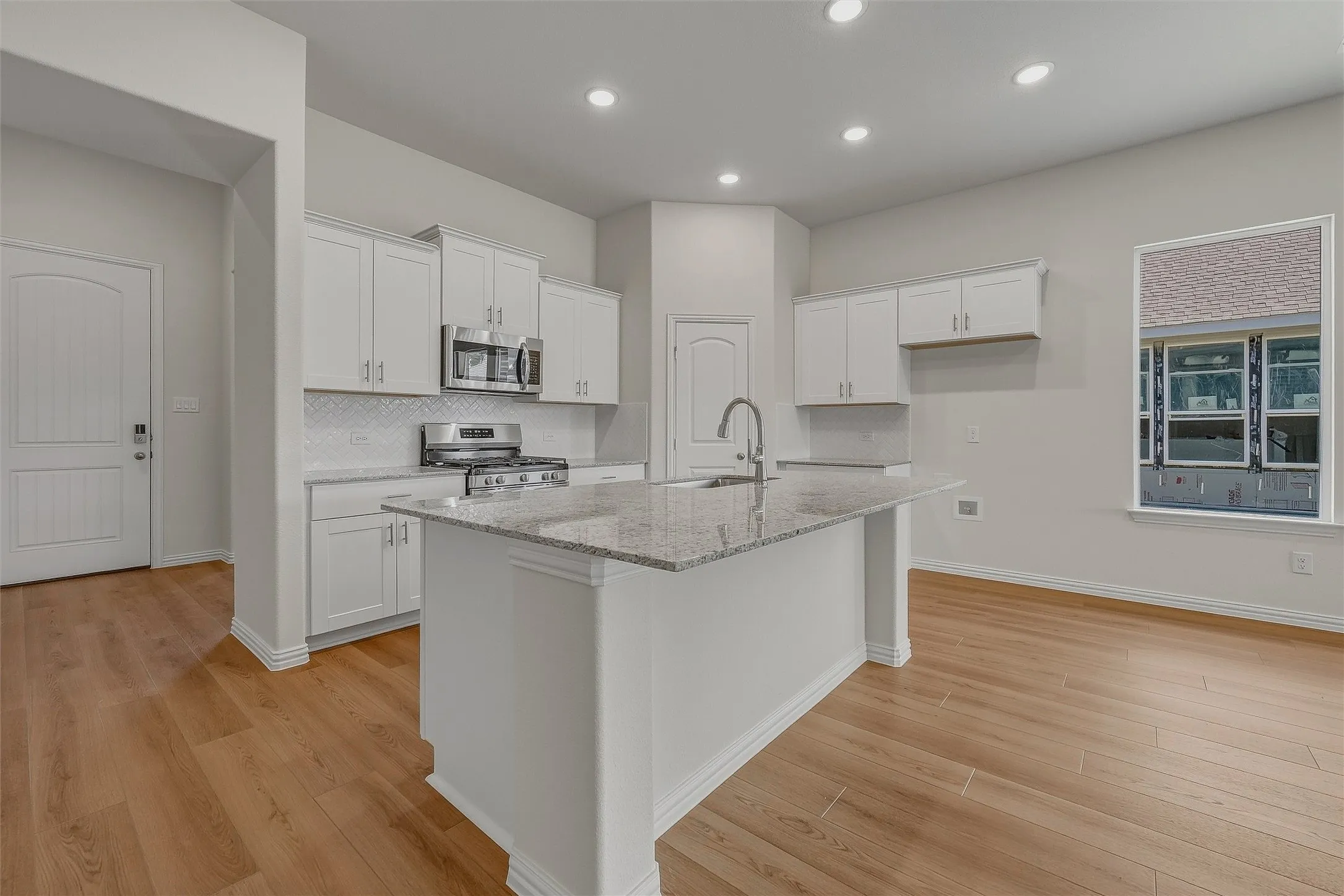Kitchen featuring a central island with countertop, shaker-style cabinetry, wood-finish flooring, recessed lighting, and stainless steel appliances