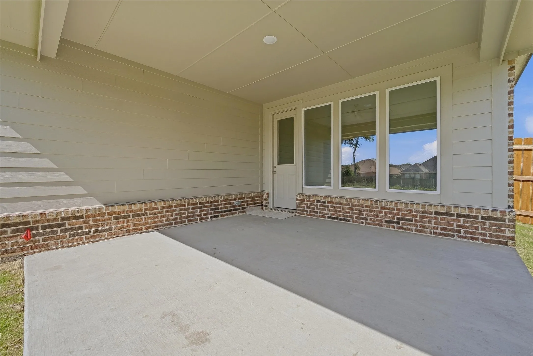 Covered patio with a concrete surface, brick base, and multiple windows