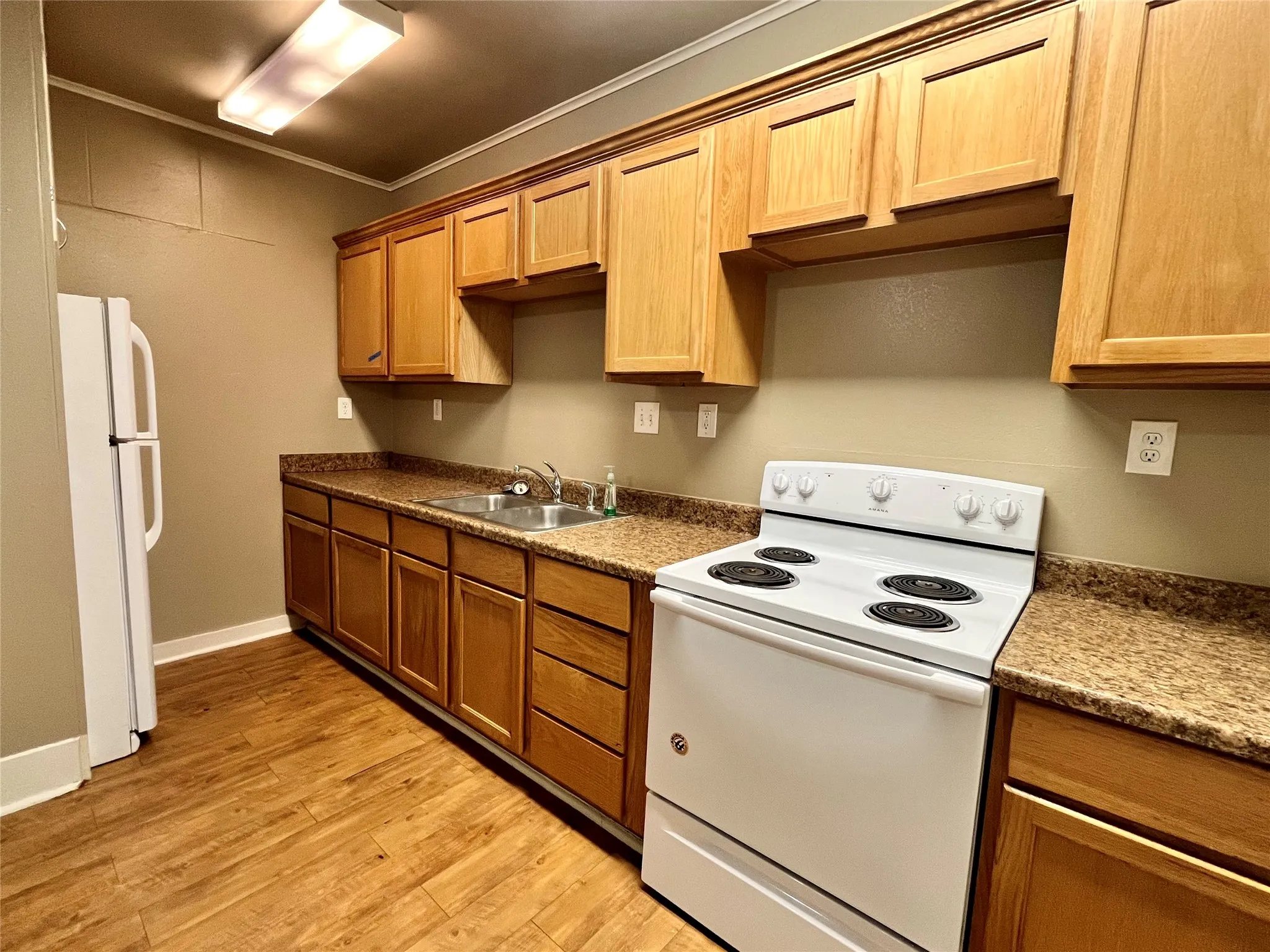 Enjoy cooking in this spacious kitchen featuring abundant warm wood cabinetry, extensive counter space, and a clean, full-sized white range.