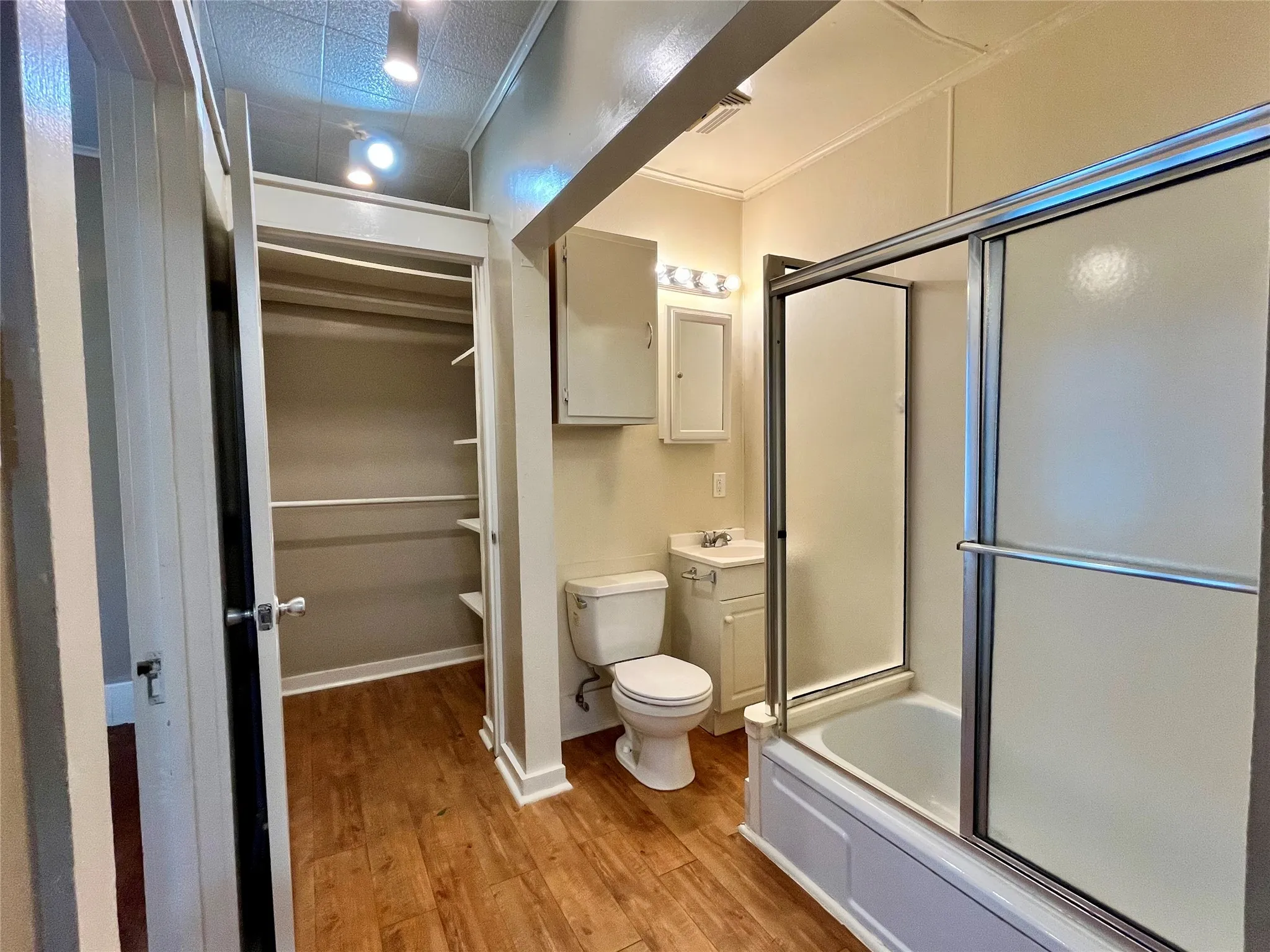 This bright, spacious bathroom offers a modern layout, a tub-and-shower combo with sleek glass doors, and seamless access to your closet.