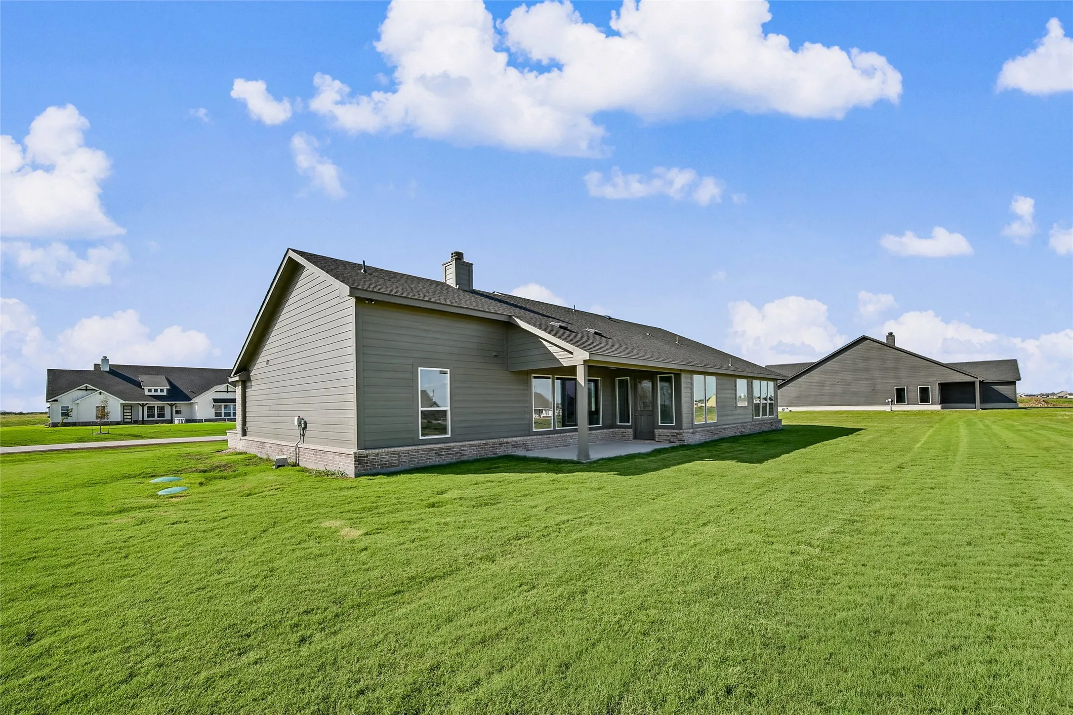 Exterior featuring horizontal lap siding, stone masonry skirting, a covered concrete patio, and a shingle roof