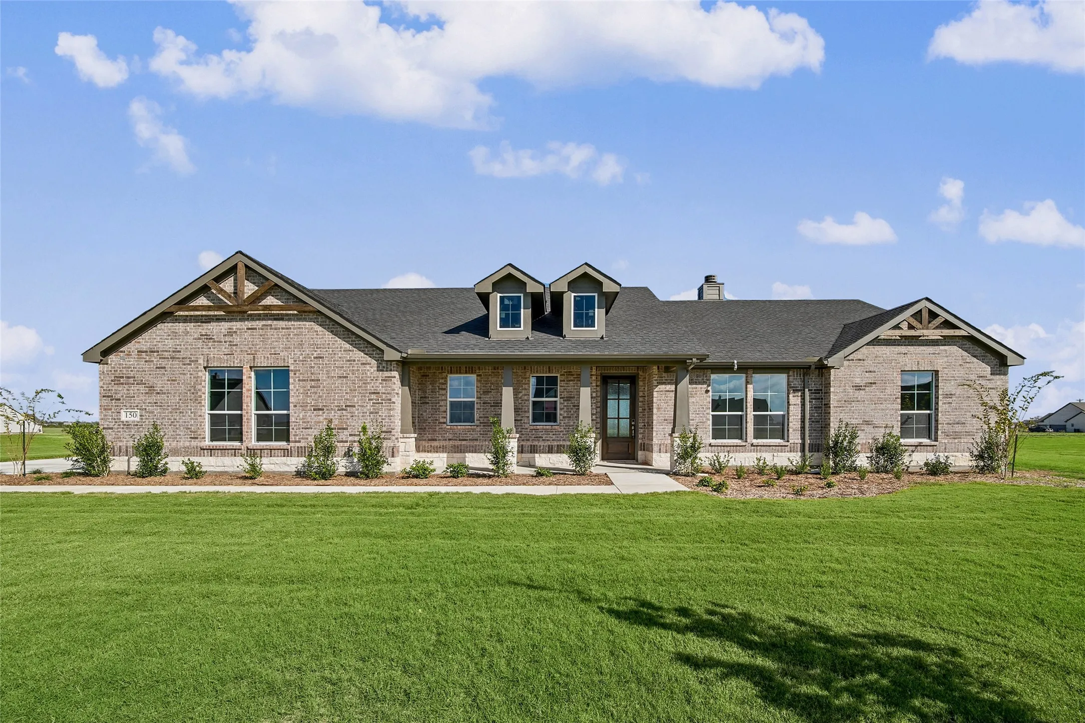 Single-story brick exterior featuring gable roof lines with decorative timber accents, a covered front entryway, and double dormer windows
