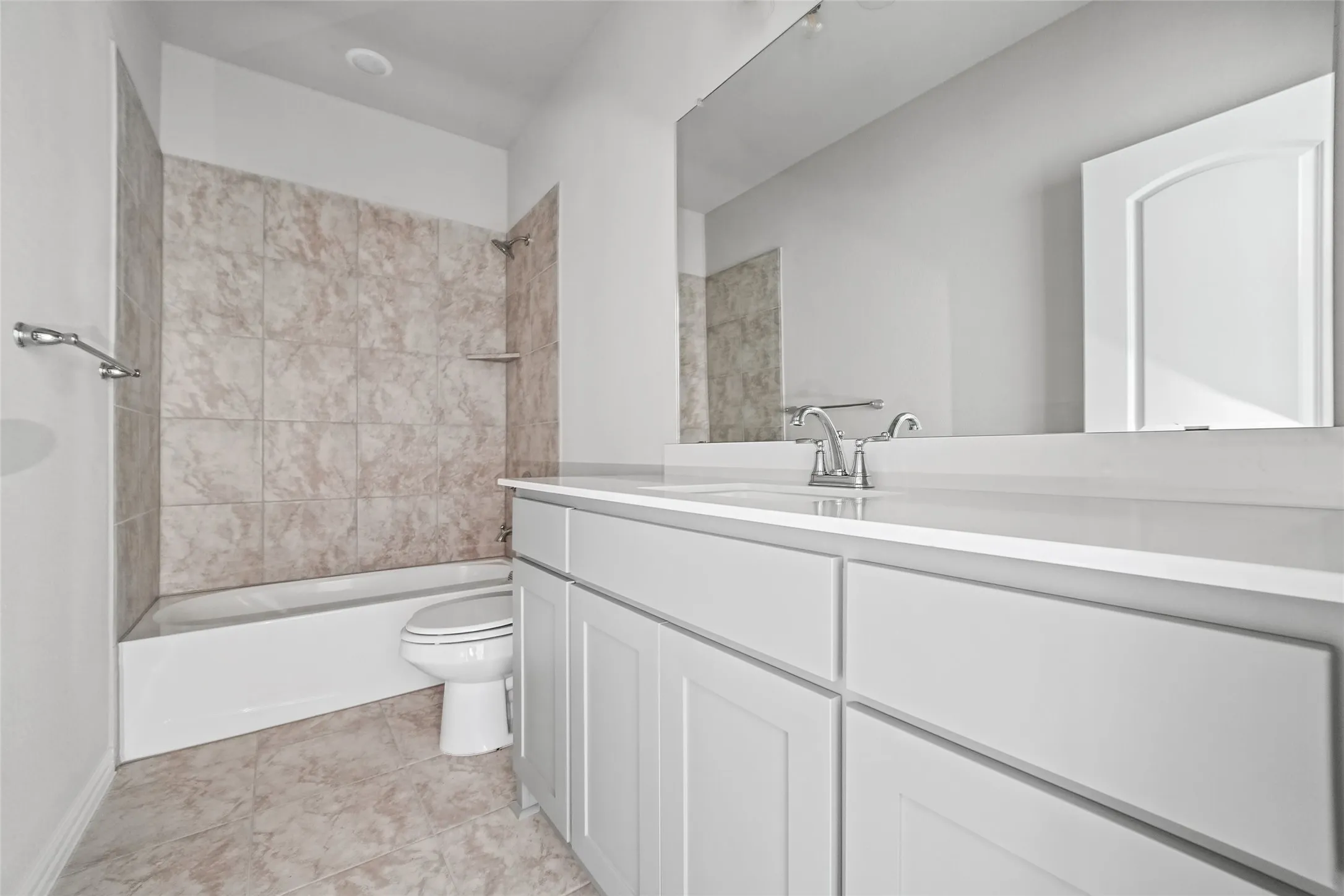 Bathroom featuring a white vanity cabinet, solid-surface countertop with an integrated sink, full-width vanity mirror, and a tub-shower combination with tiled surround