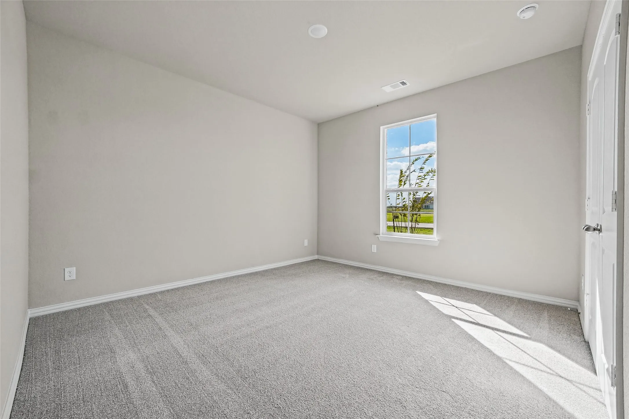 Neutral-toned interior featuring wall-to-wall carpeting, recessed lighting, and a single-pane window with a multi-lite grid design
