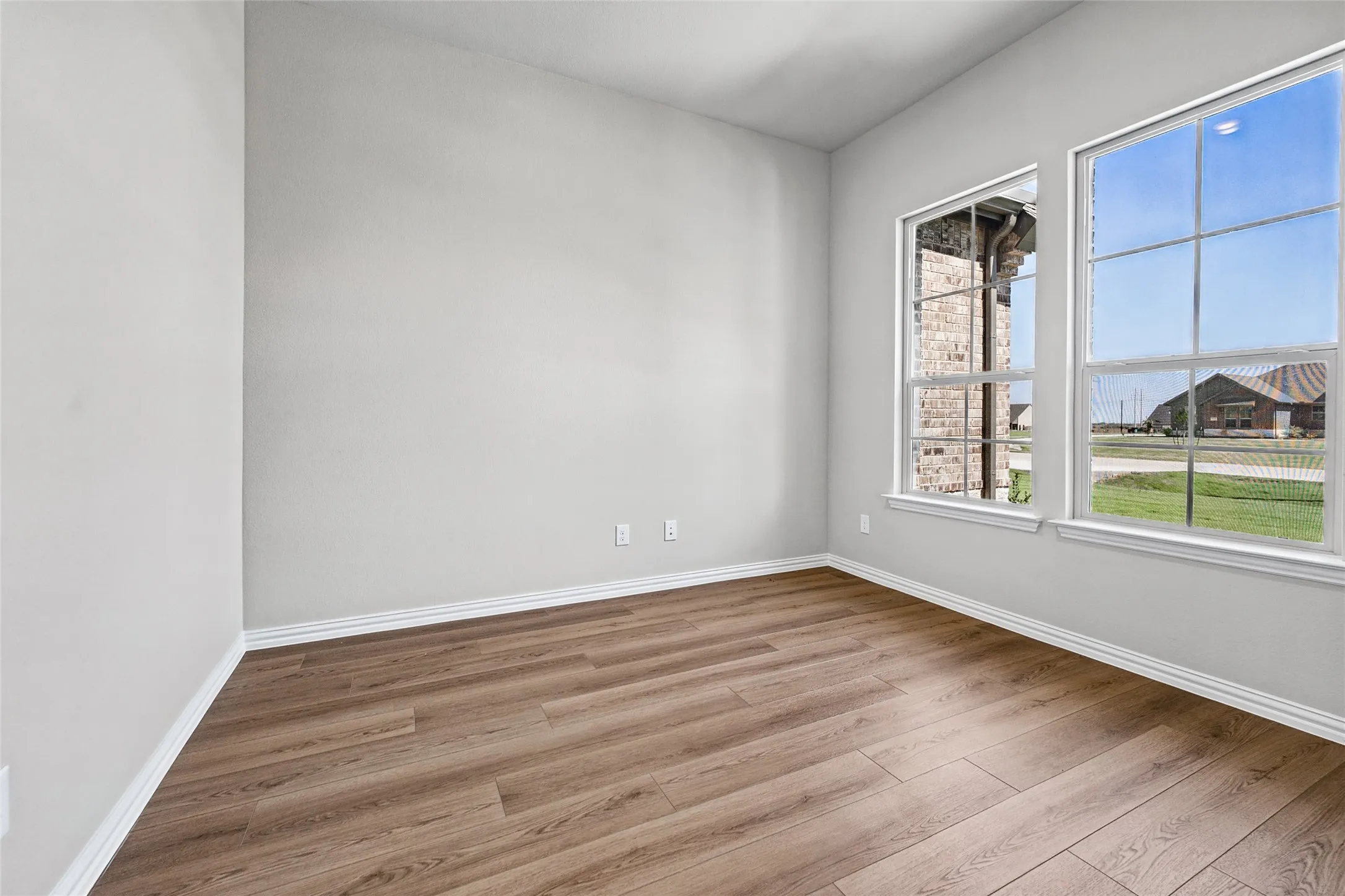 Wood-finish flooring, white walls, and two large windows with white trim