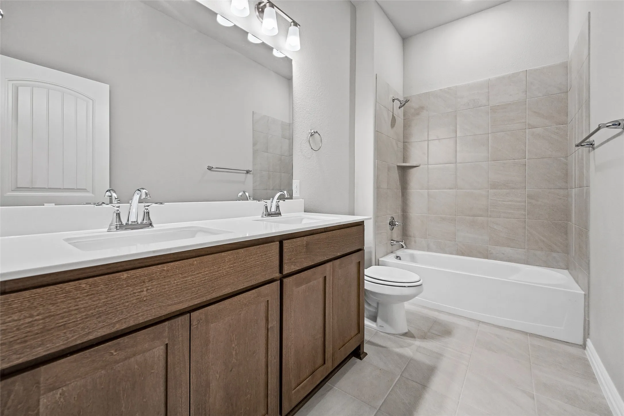 Dual vanity with white undermount sinks, wood-finish cabinetry, and chrome fixtures