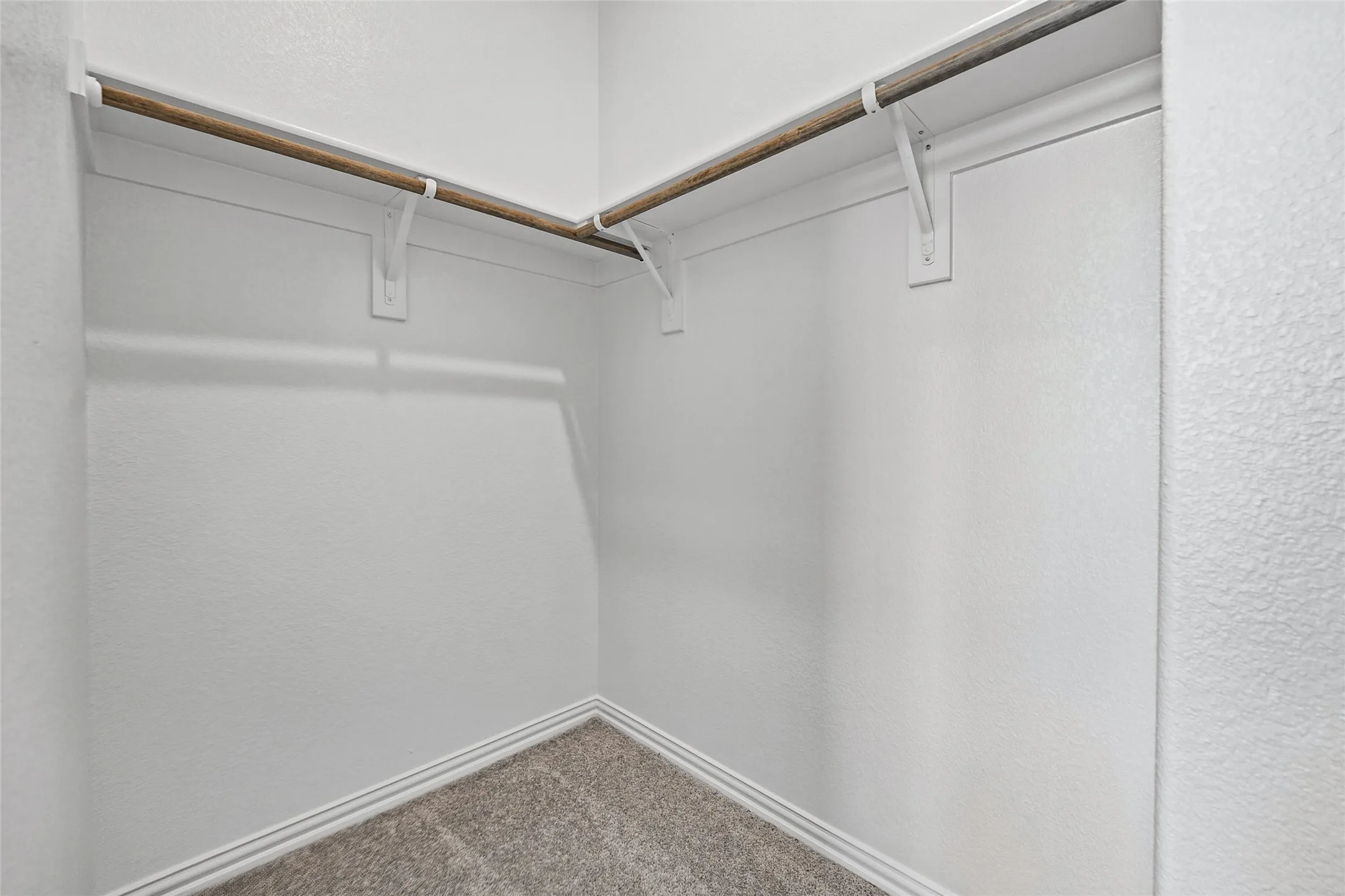 Corner closet with white walls and light-colored carpeting