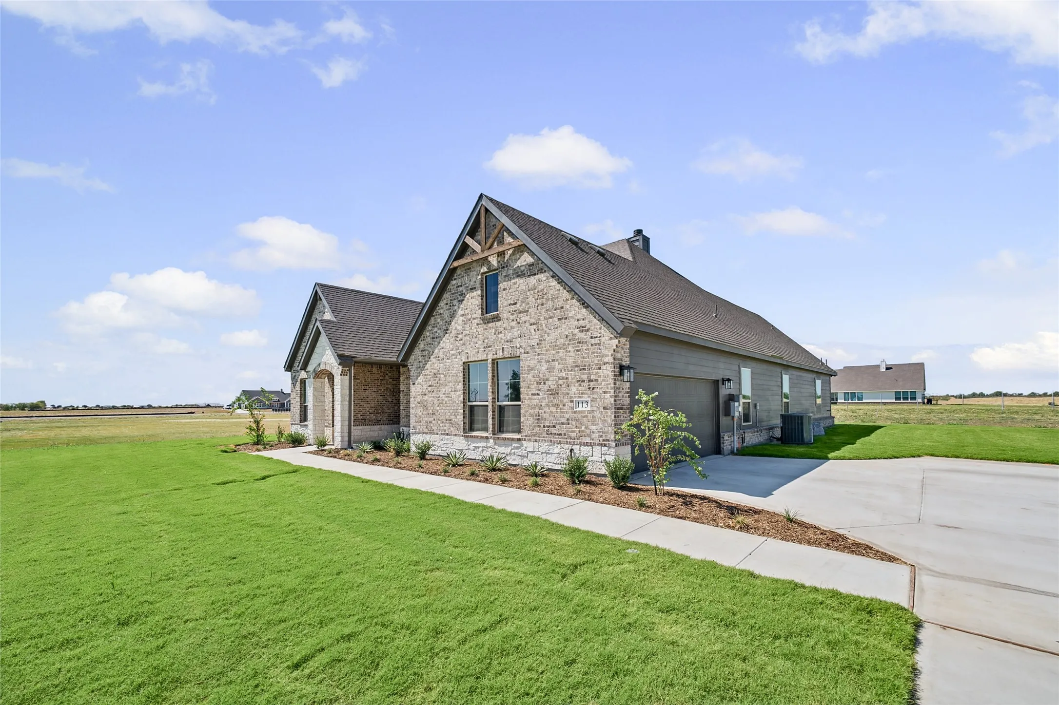 Stone and siding exterior with a dark shingle roof, featuring a concrete driveway and walkway