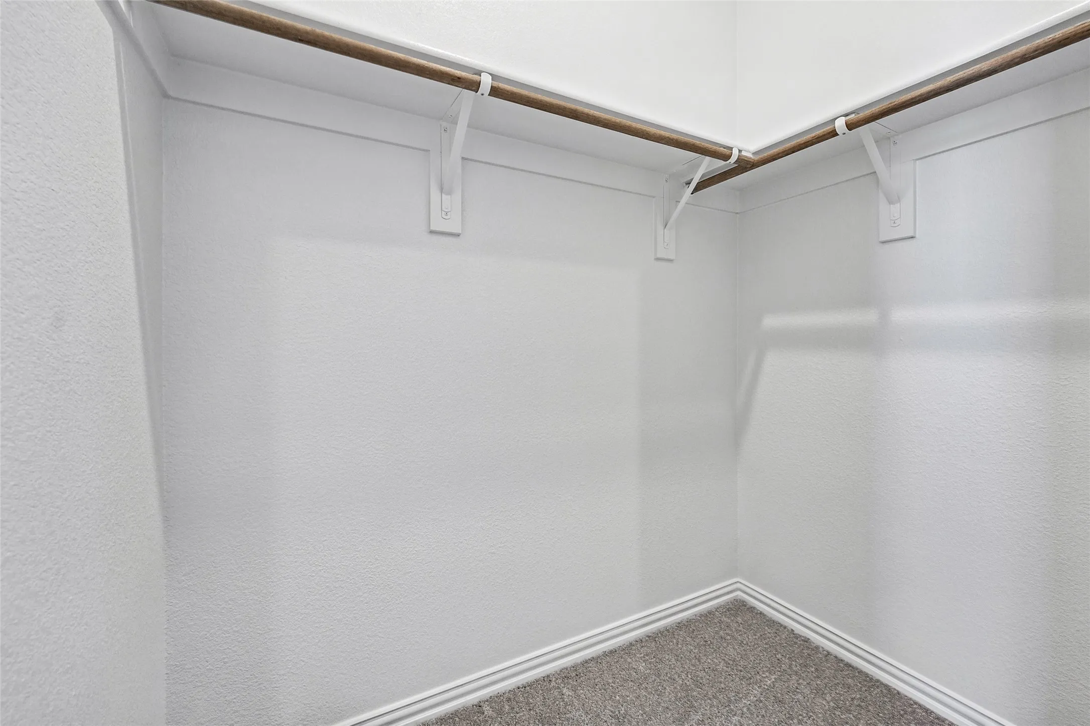 Corner closet with dual wooden hanging rods and wall-mounted brackets
