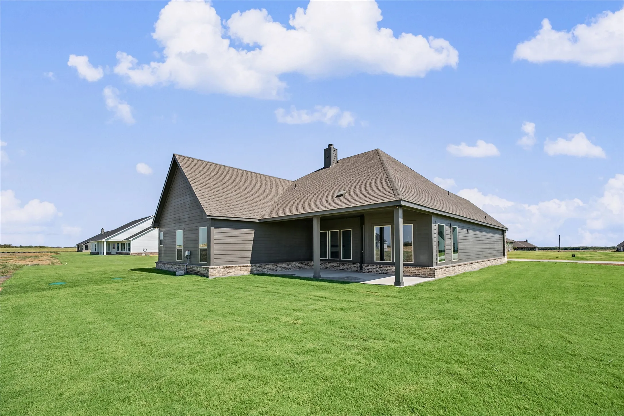 Spacious rear yard with green lawn, covered patio, and side-gabled roofline
