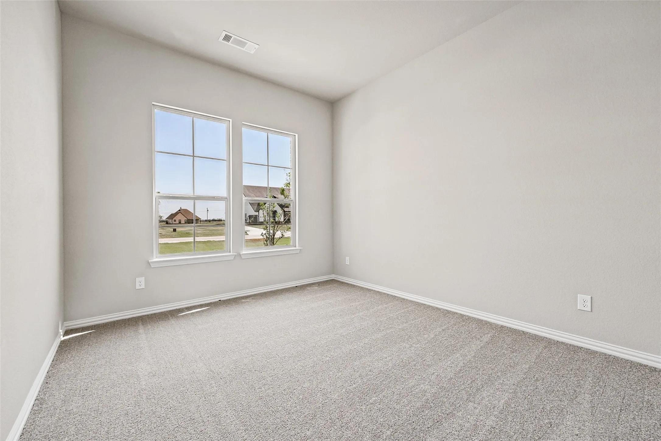 Bright room featuring two large windows, neutral-toned walls, and plush carpeting